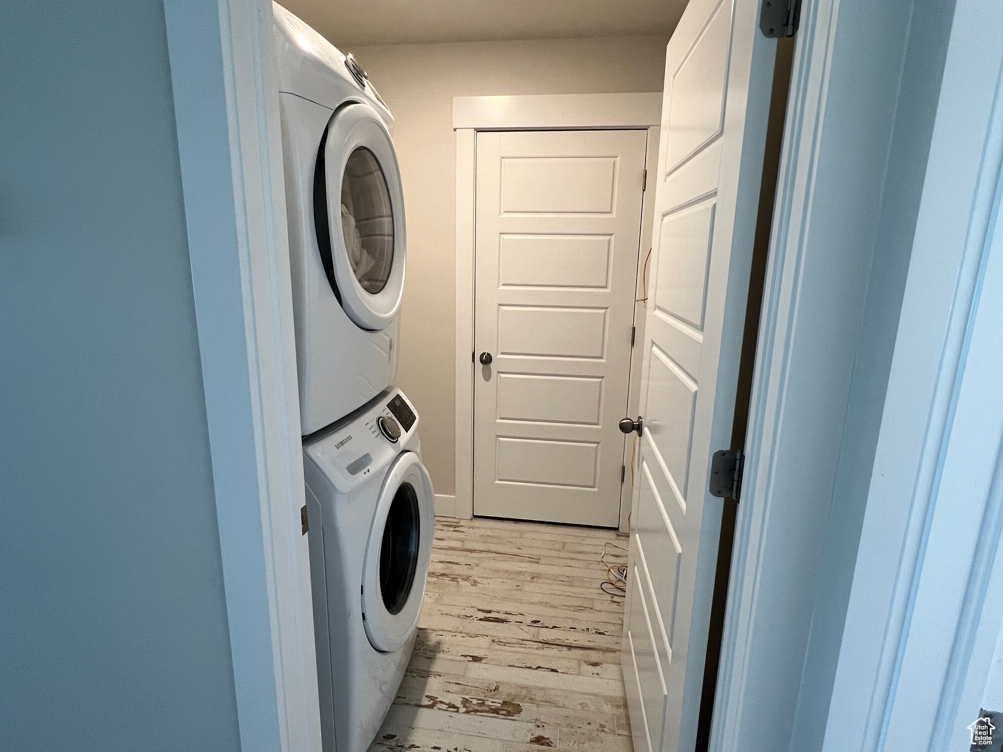 Clothes washing area with stacked washer / dryer and light hardwood / wood-style flooring