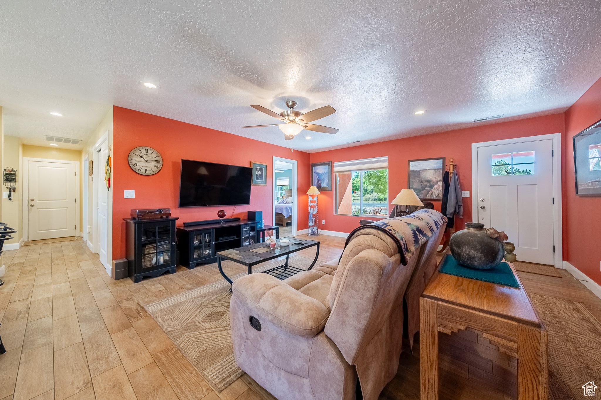 Living room featuring light wood-type flooring, a textured ceiling, and ceiling fan