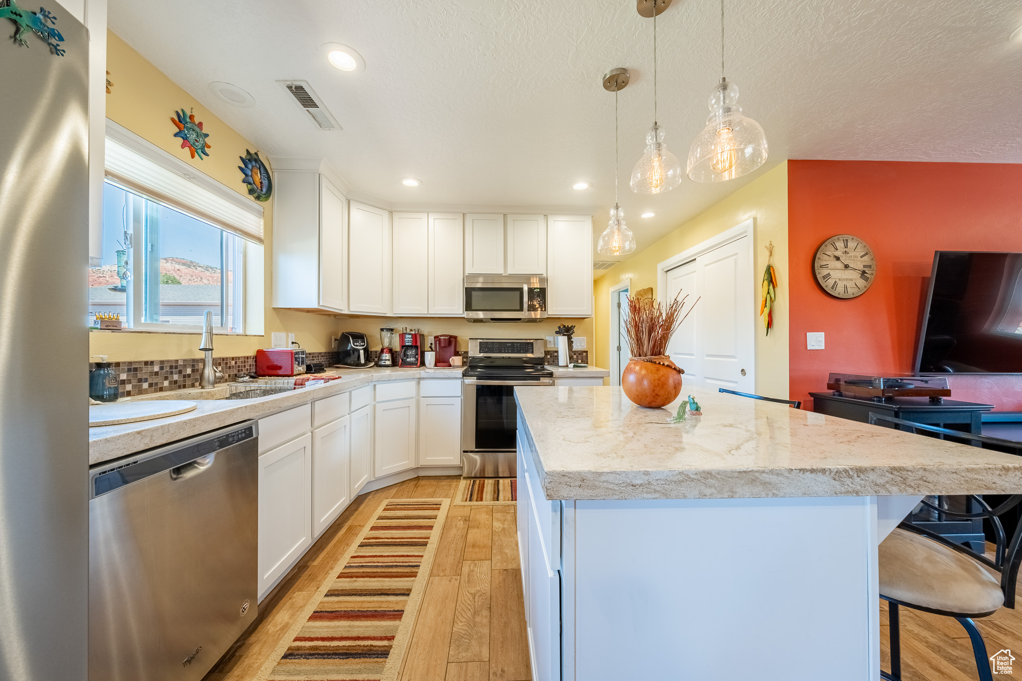 Kitchen featuring stainless steel appliances, light hardwood / wood-style floors, white cabinets, and a kitchen island