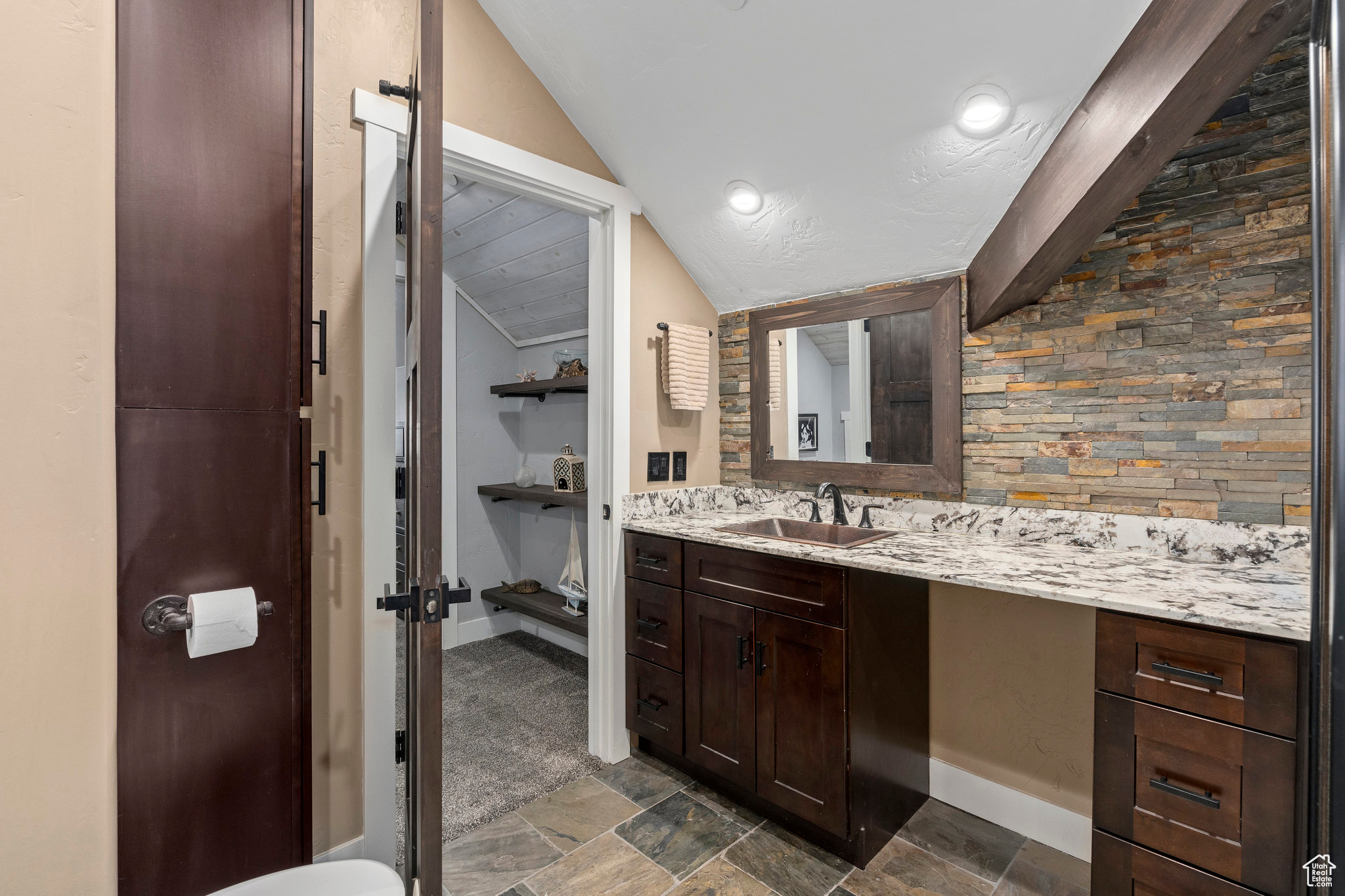 Bathroom featuring tile flooring, vanity with extensive cabinet space, and vaulted ceiling