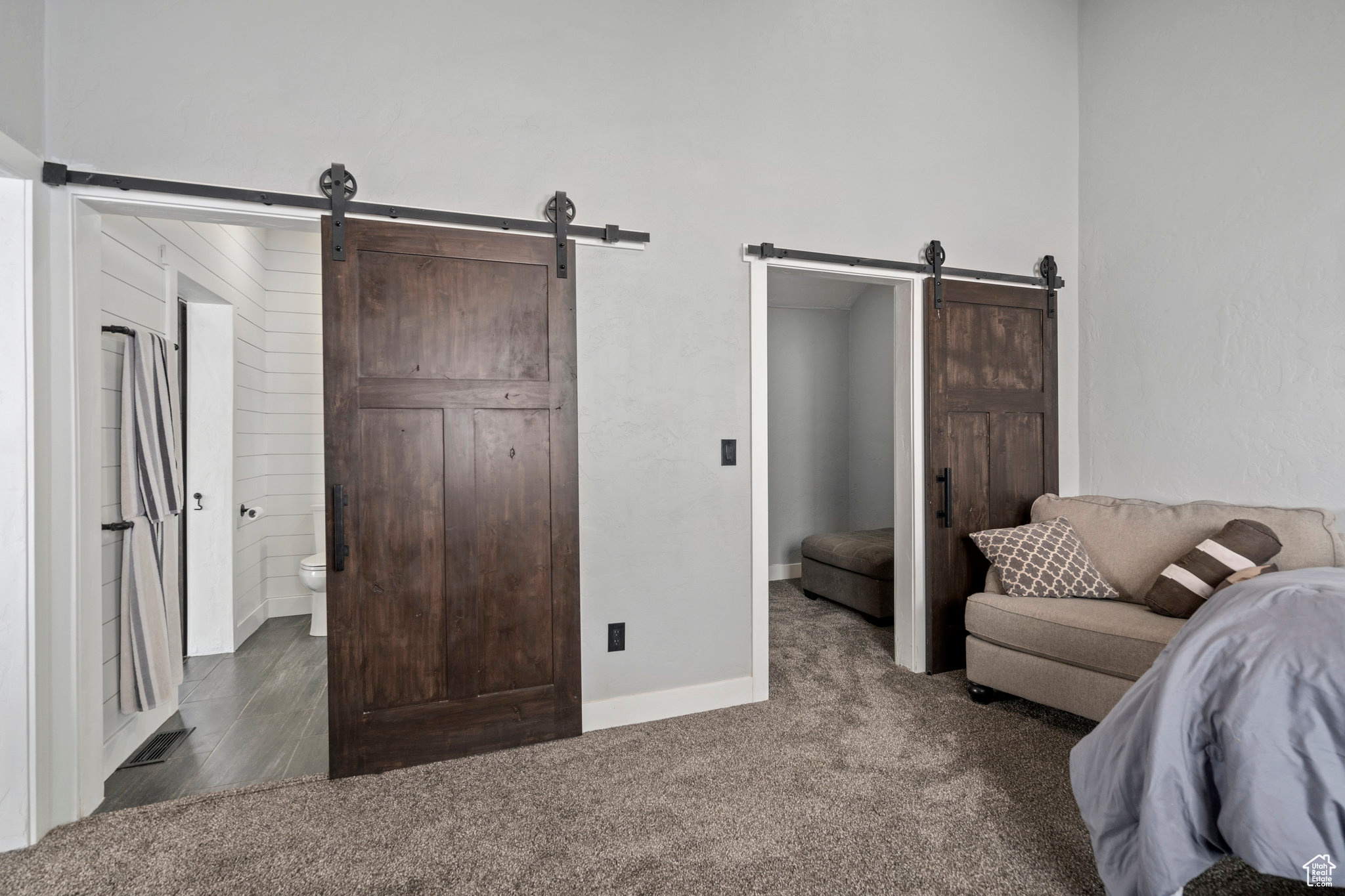 Carpeted bedroom with a barn door and ensuite bathroom