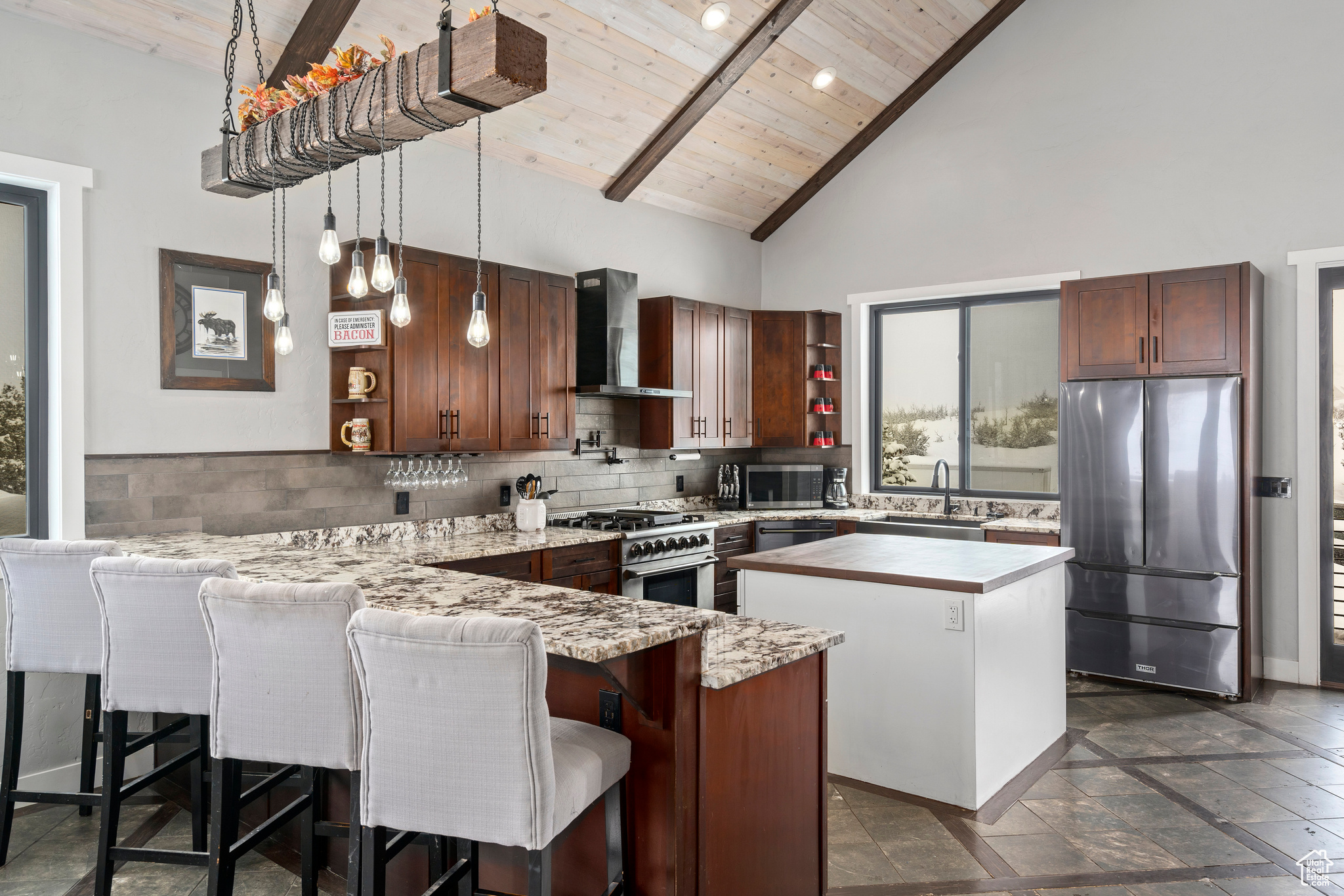 Kitchen with high vaulted ceiling, stainless steel appliances, wood ceiling, and wall chimney exhaust hood