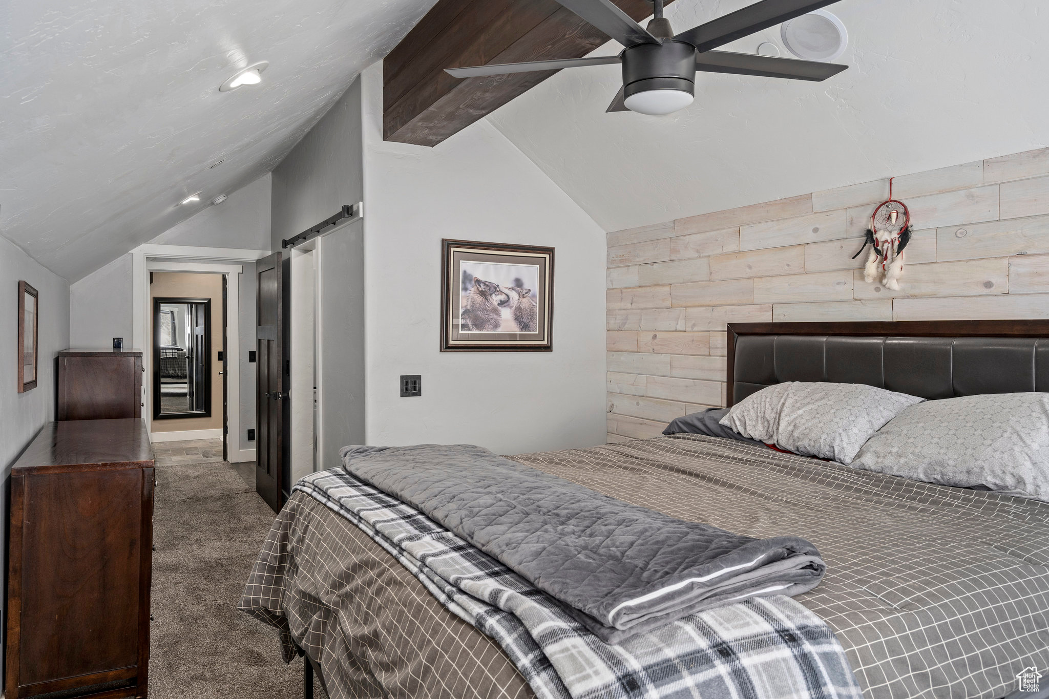 Carpeted bedroom featuring a barn door, ceiling fan, and lofted ceiling