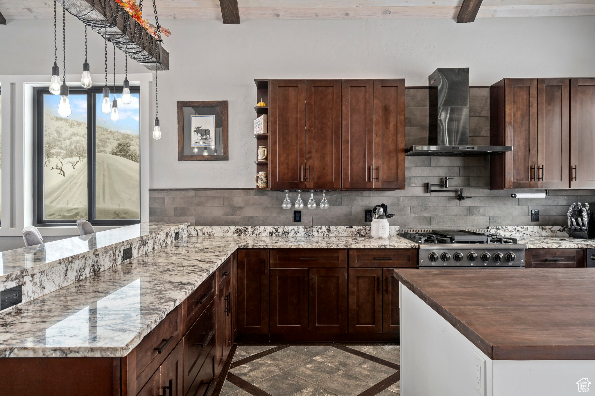 Kitchen with backsplash, range, dark tile flooring, wall chimney exhaust hood, and beam ceiling