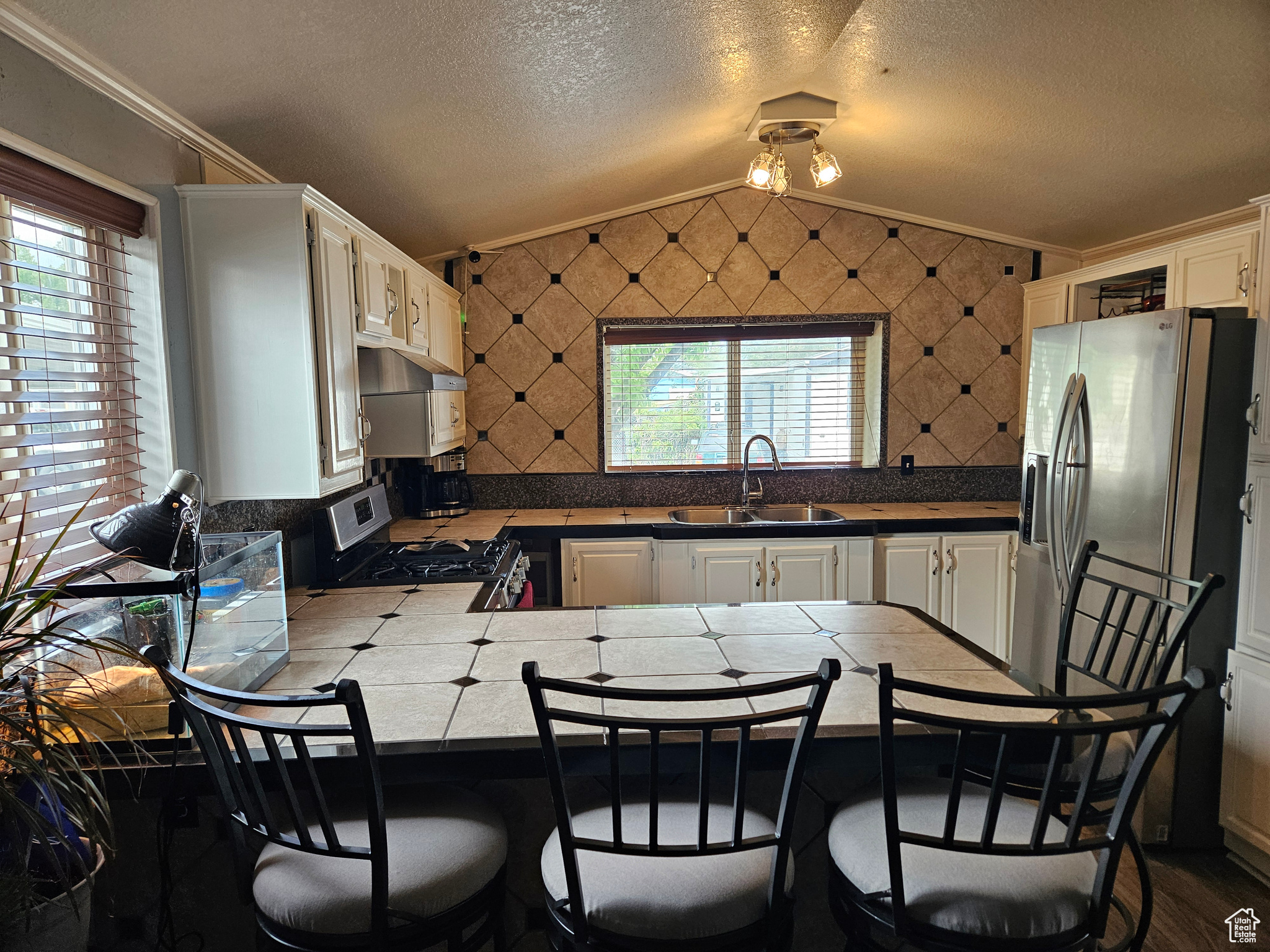 Kitchen with gas range oven, kitchen peninsula, crown molding, sink, and lofted ceiling