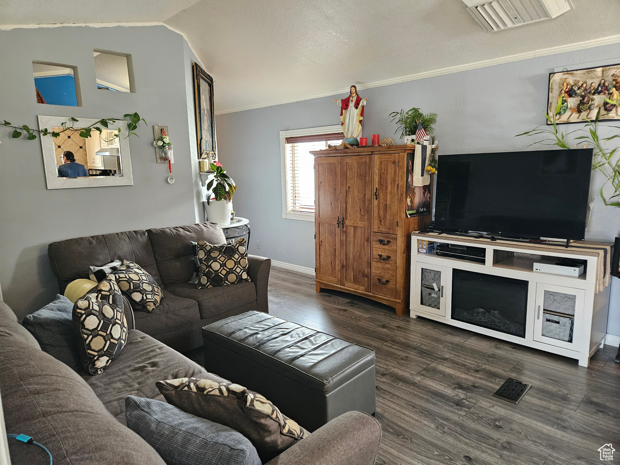 Living room with vaulted ceiling, ornamental molding, and dark hardwood / wood-style floors