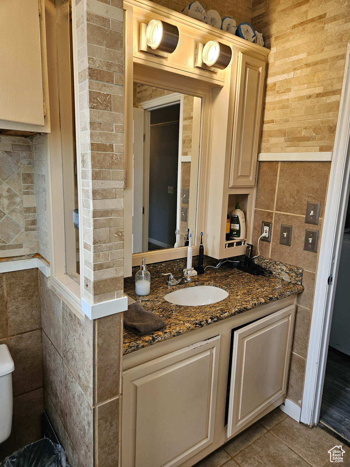 Bathroom with tile walls, tile flooring, vanity, and toilet