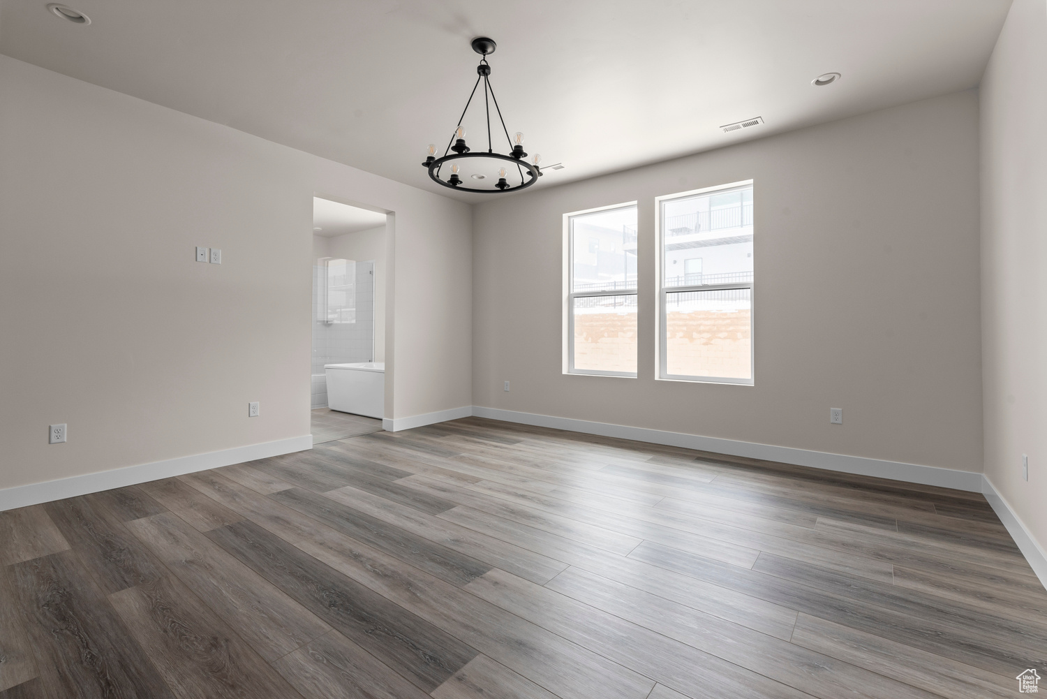 Spare room featuring a notable chandelier and wood-type flooring