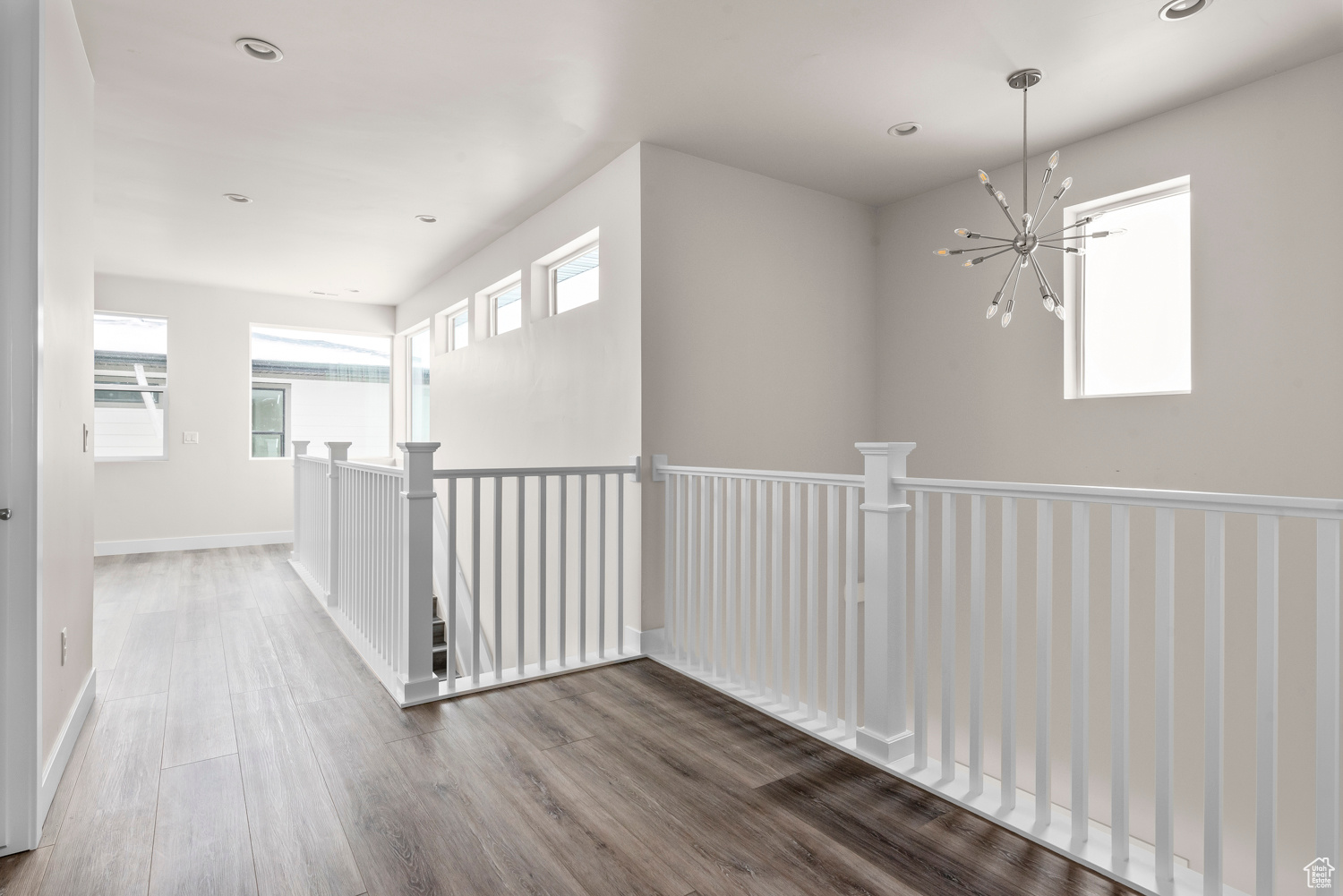 Corridor with a notable chandelier and dark hardwood / wood-style flooring