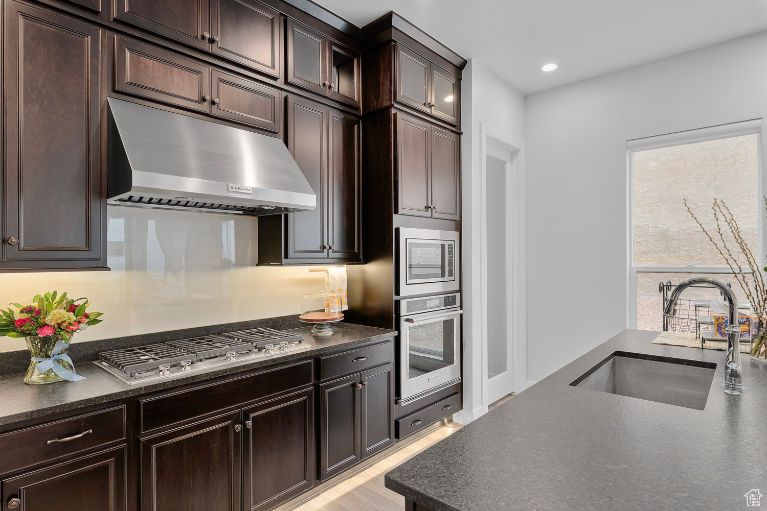 Kitchen featuring stainless steel appliances, sink, light wood-type flooring, and dark brown cabinetry