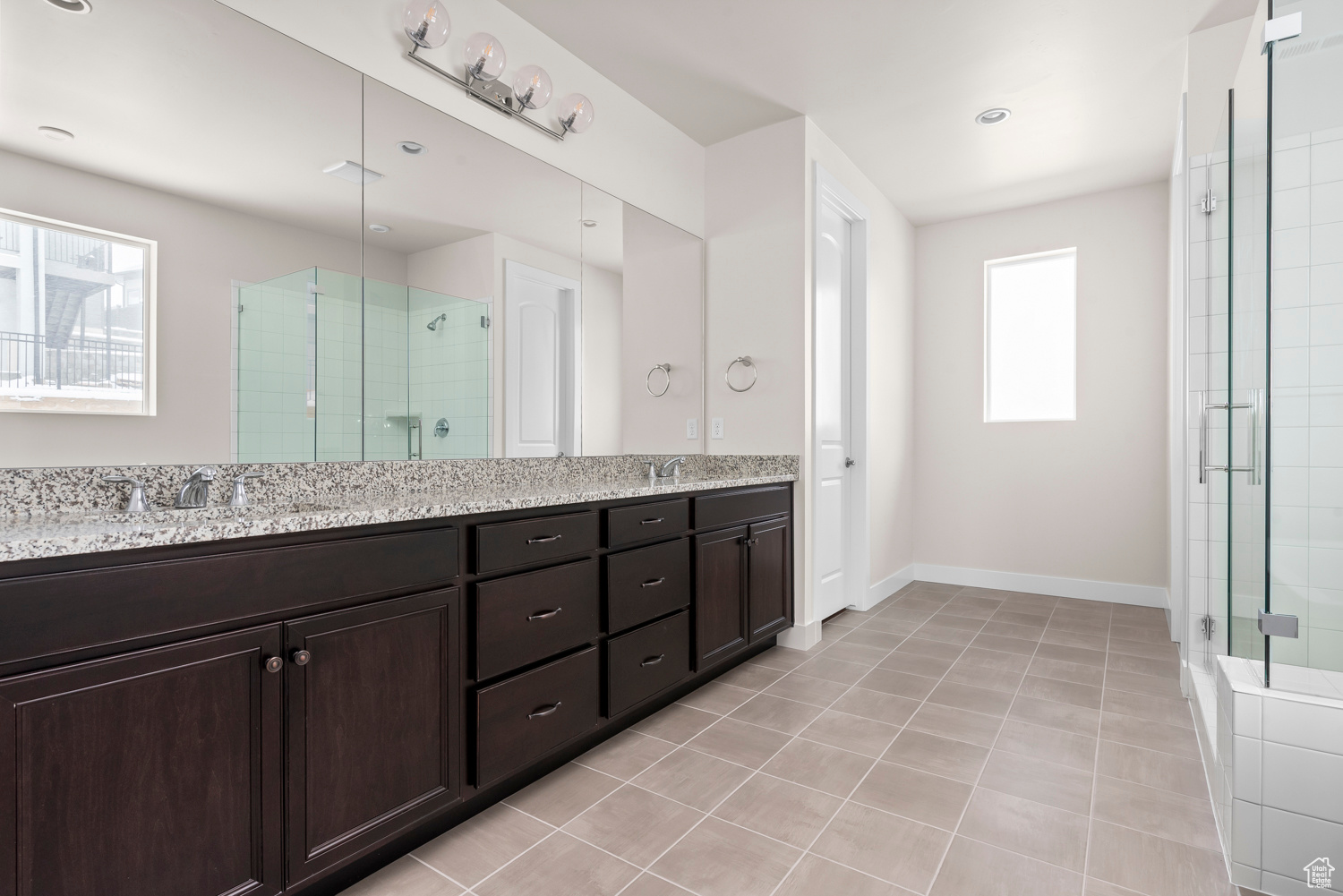 Bathroom with a shower with door, tile flooring, and double vanity