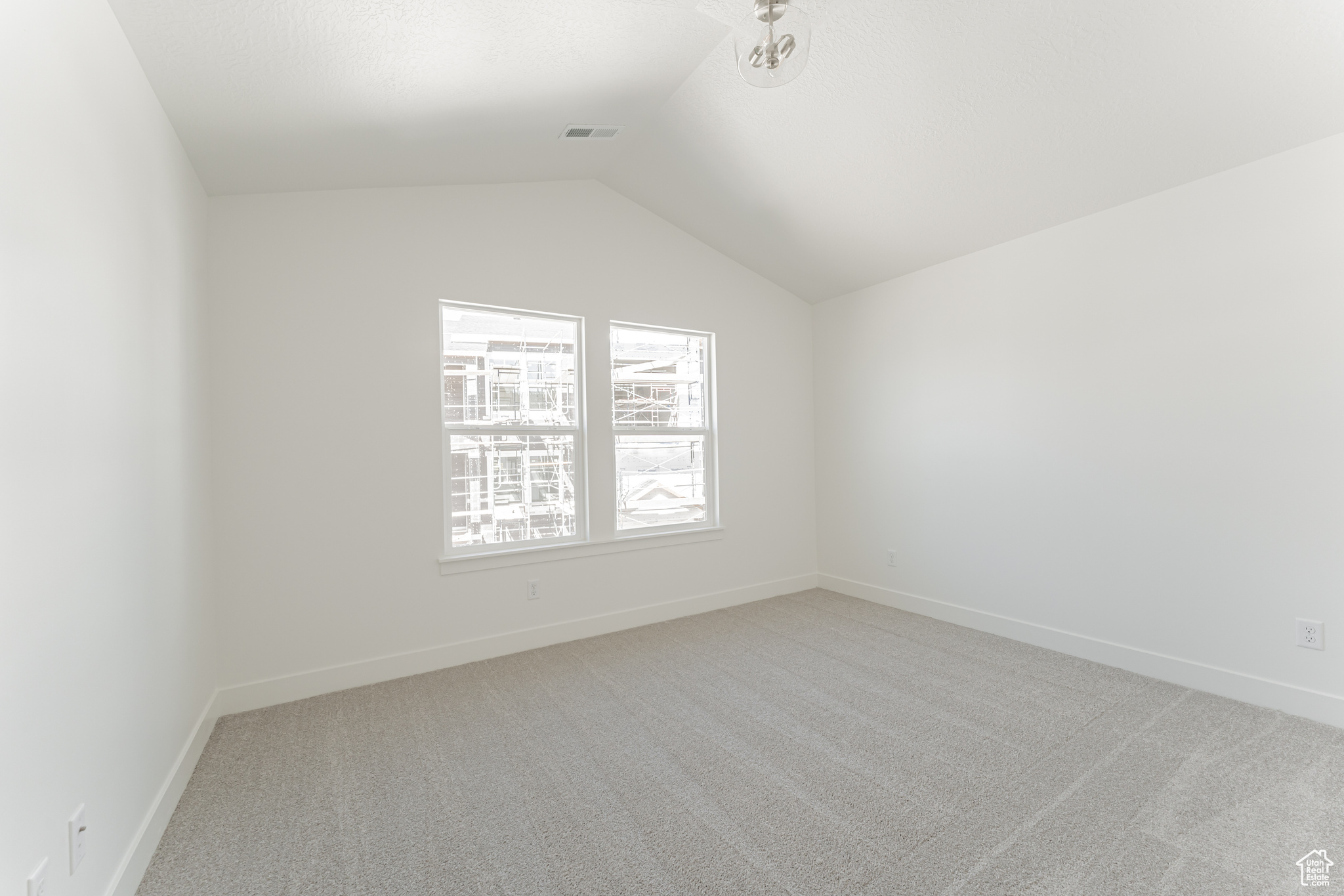 Carpeted empty room featuring vaulted ceiling