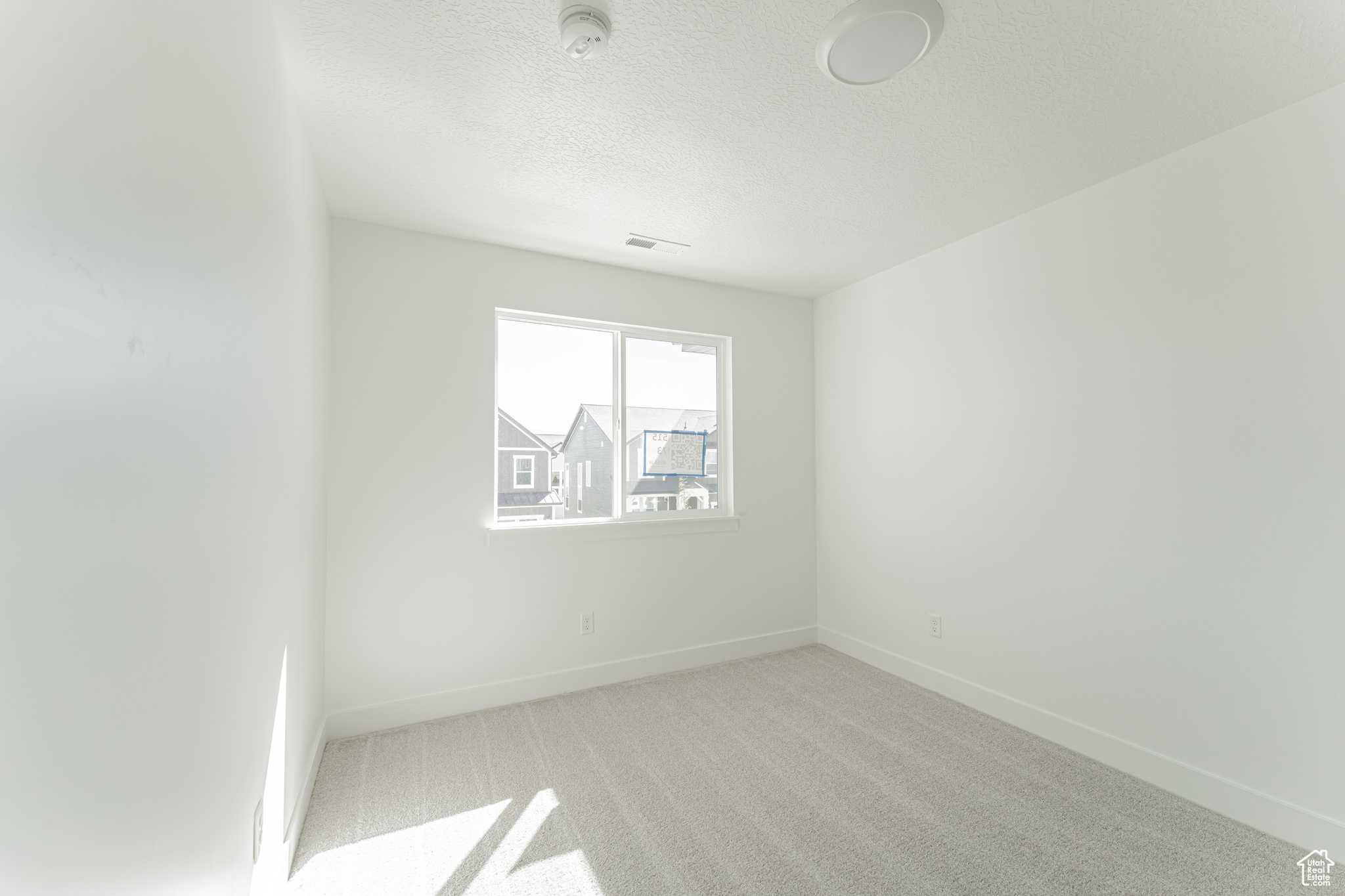 Carpeted spare room featuring a textured ceiling