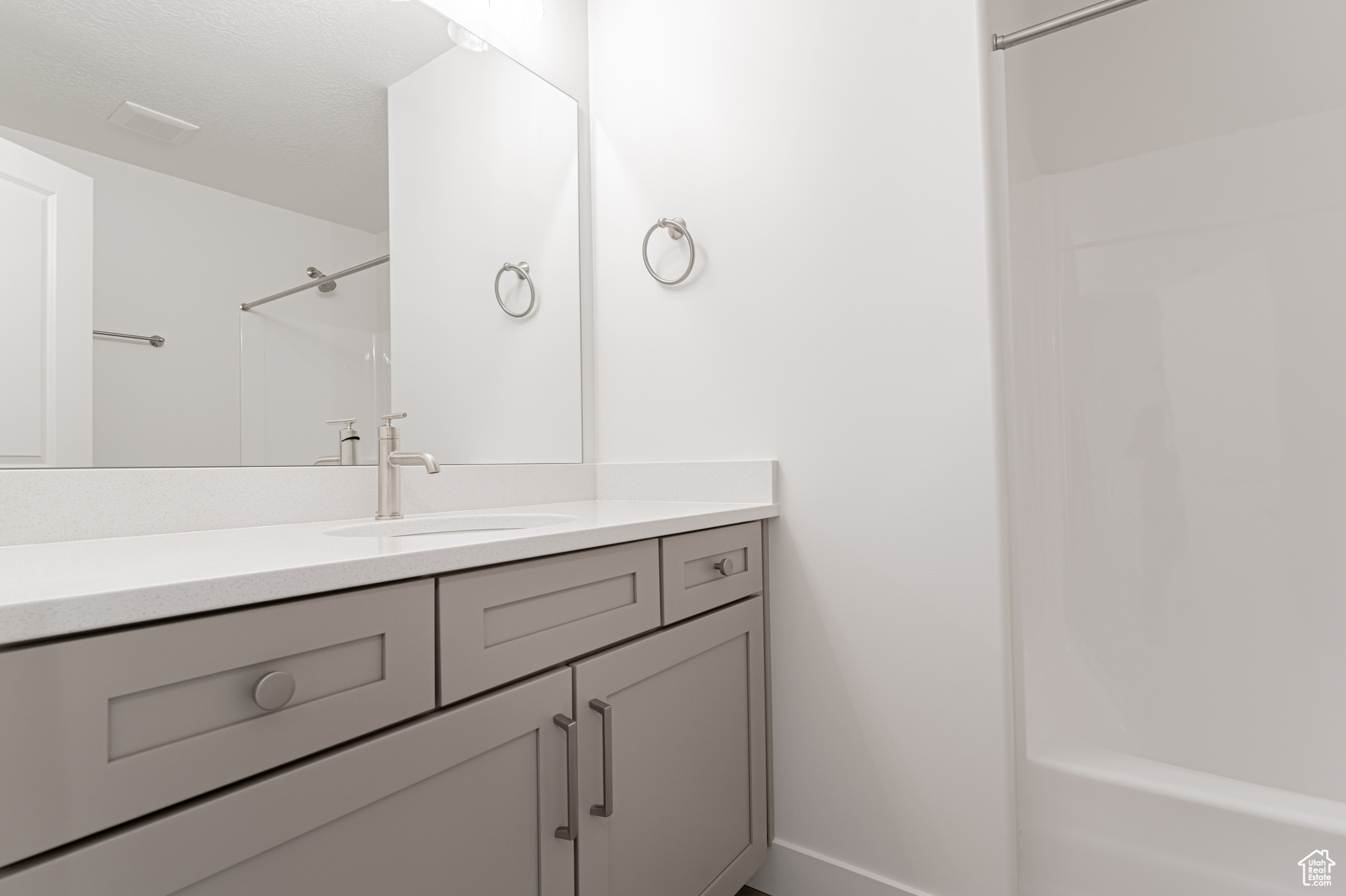 Bathroom with a textured ceiling, shower / washtub combination, and vanity