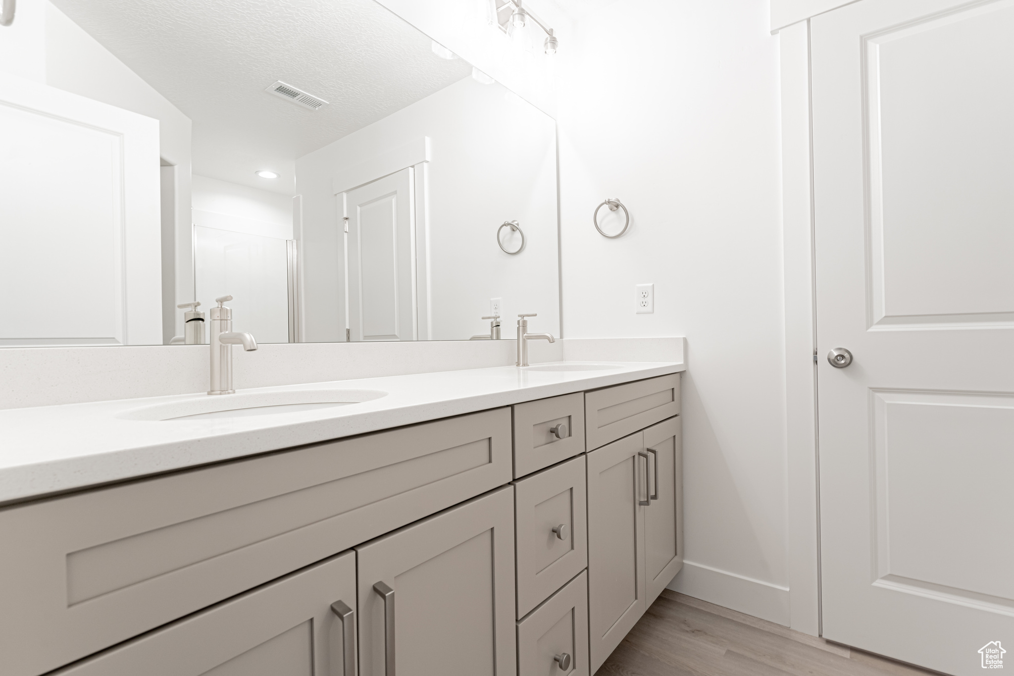 Bathroom with a textured ceiling, wood-type flooring, and vanity