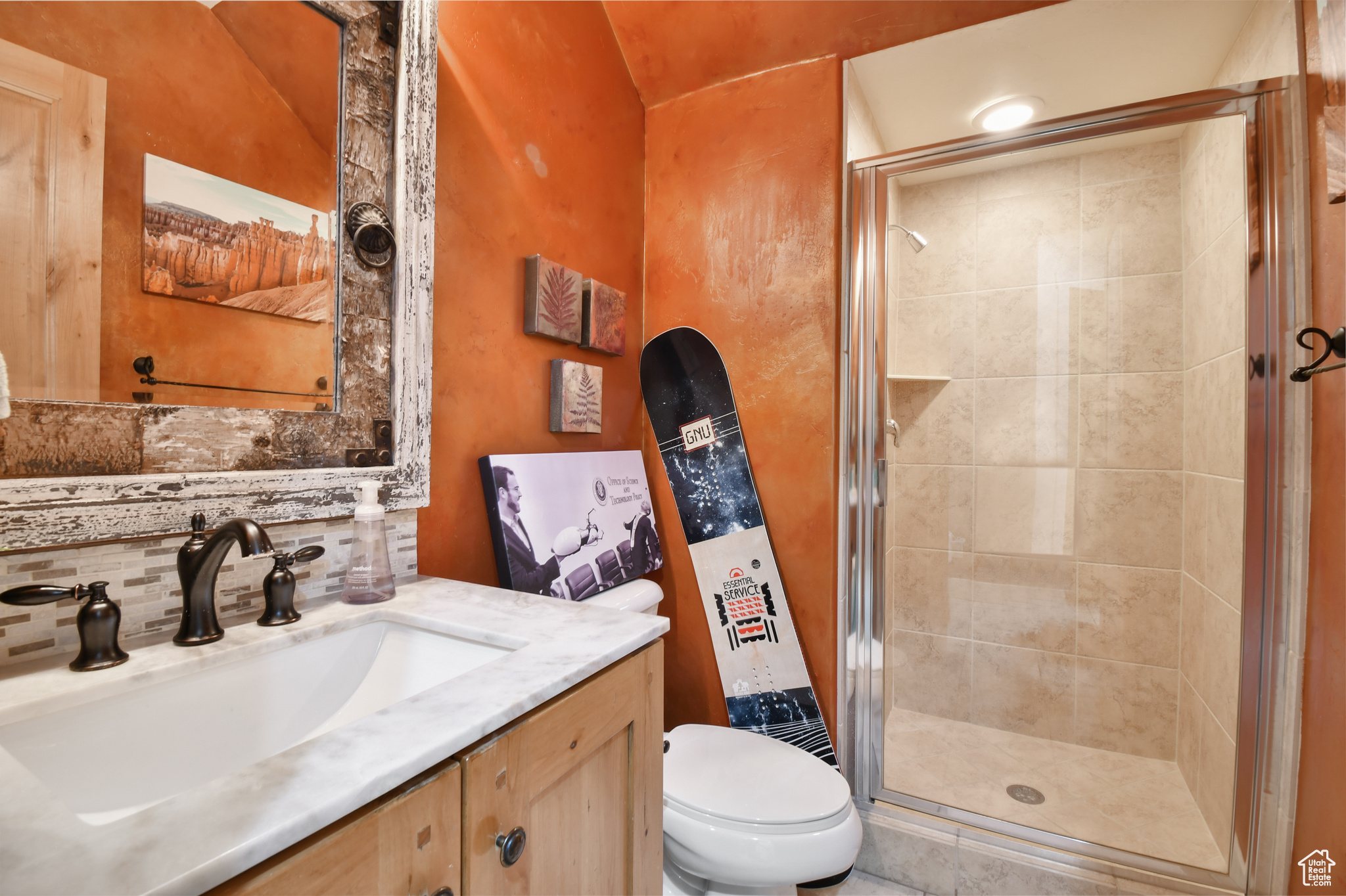 Bathroom with a shower with shower door, tasteful backsplash, toilet, and vanity