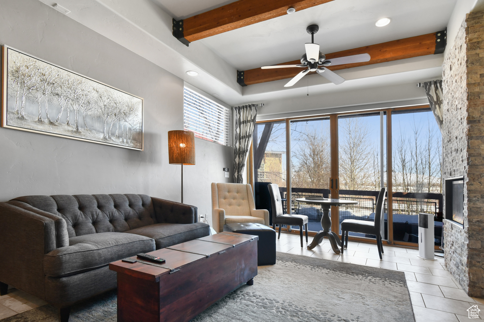 Living room featuring beamed ceiling, ceiling fan, and tile floors