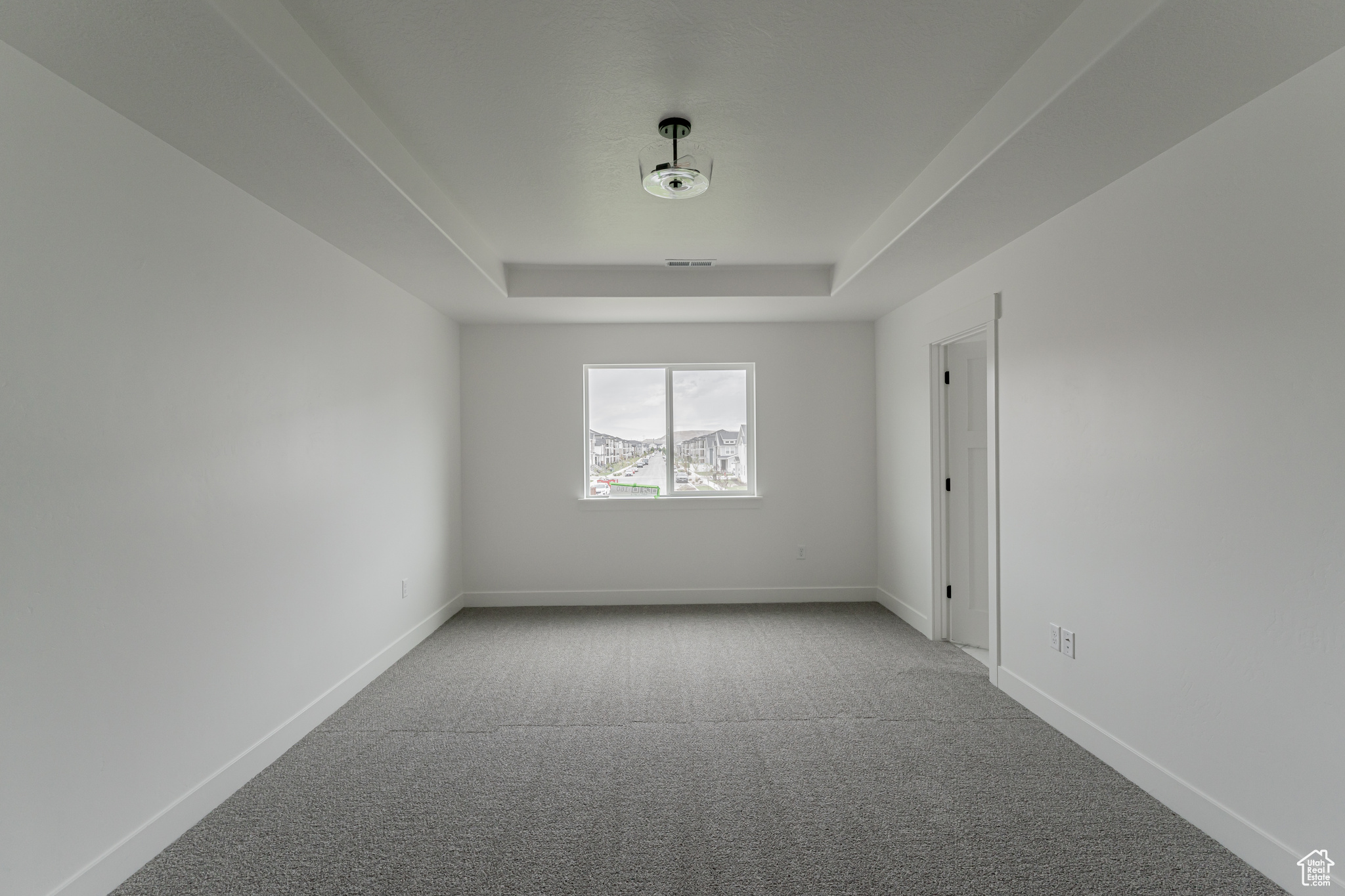 Carpeted empty room featuring a raised ceiling