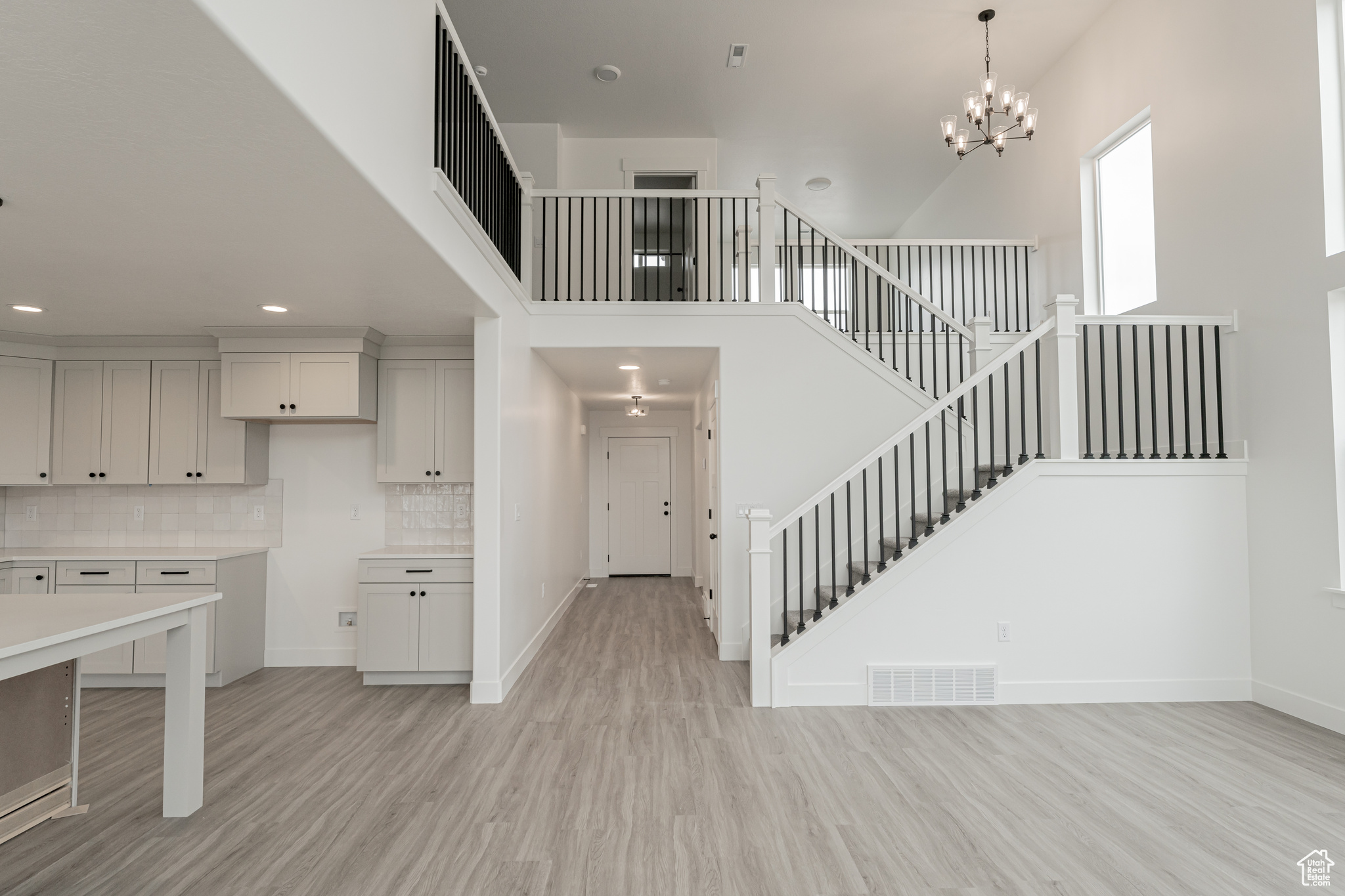 Kitchen with backsplash, a towering ceiling, and light hardwood / wood-style flooring