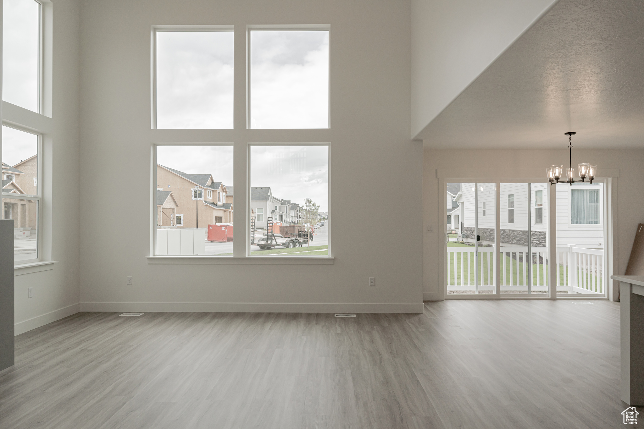 Spare room with a textured ceiling, light wood-type flooring, plenty of natural light, and a chandelier