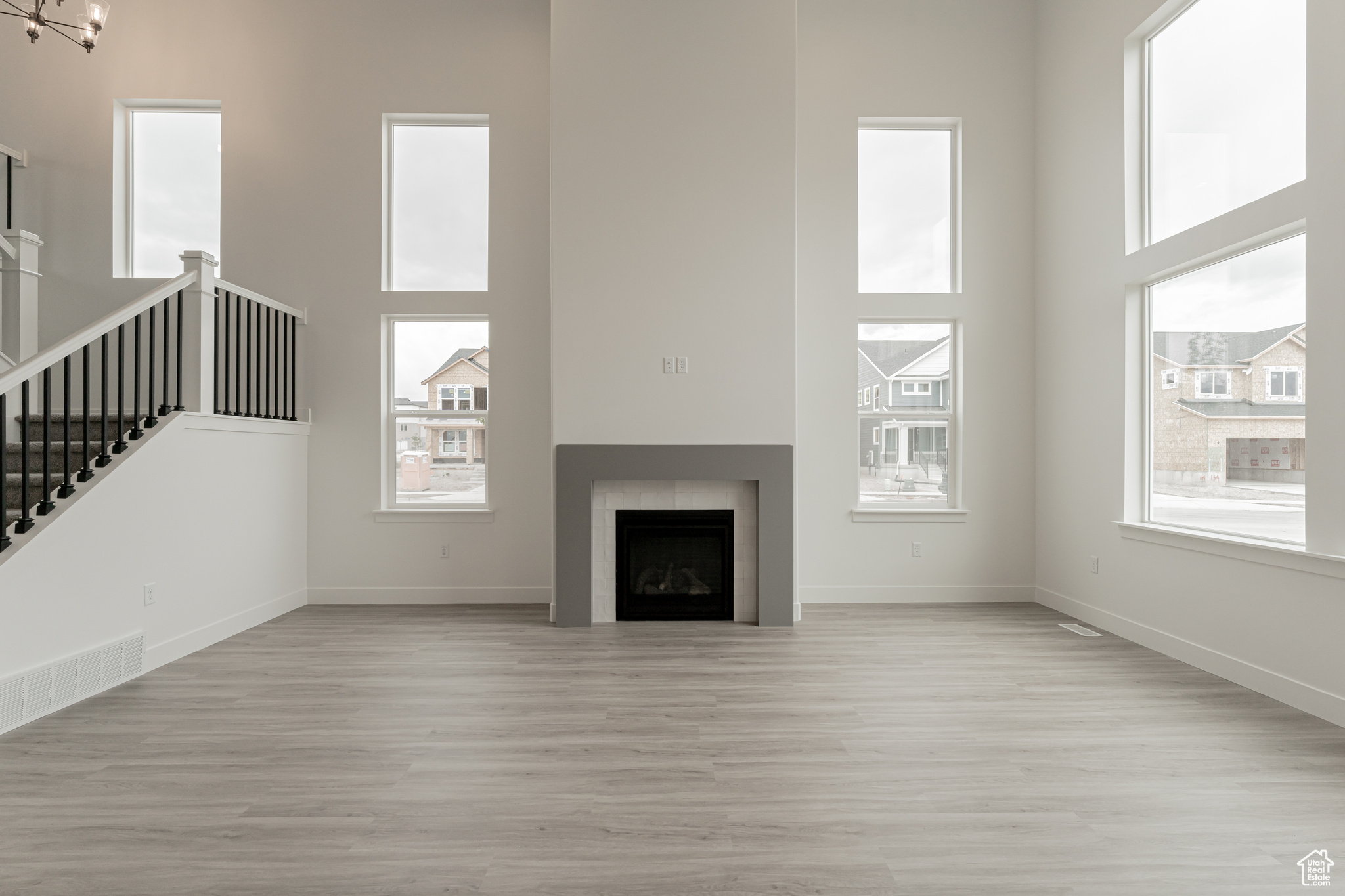 Unfurnished living room featuring light wood-type flooring, plenty of natural light, and a high ceiling