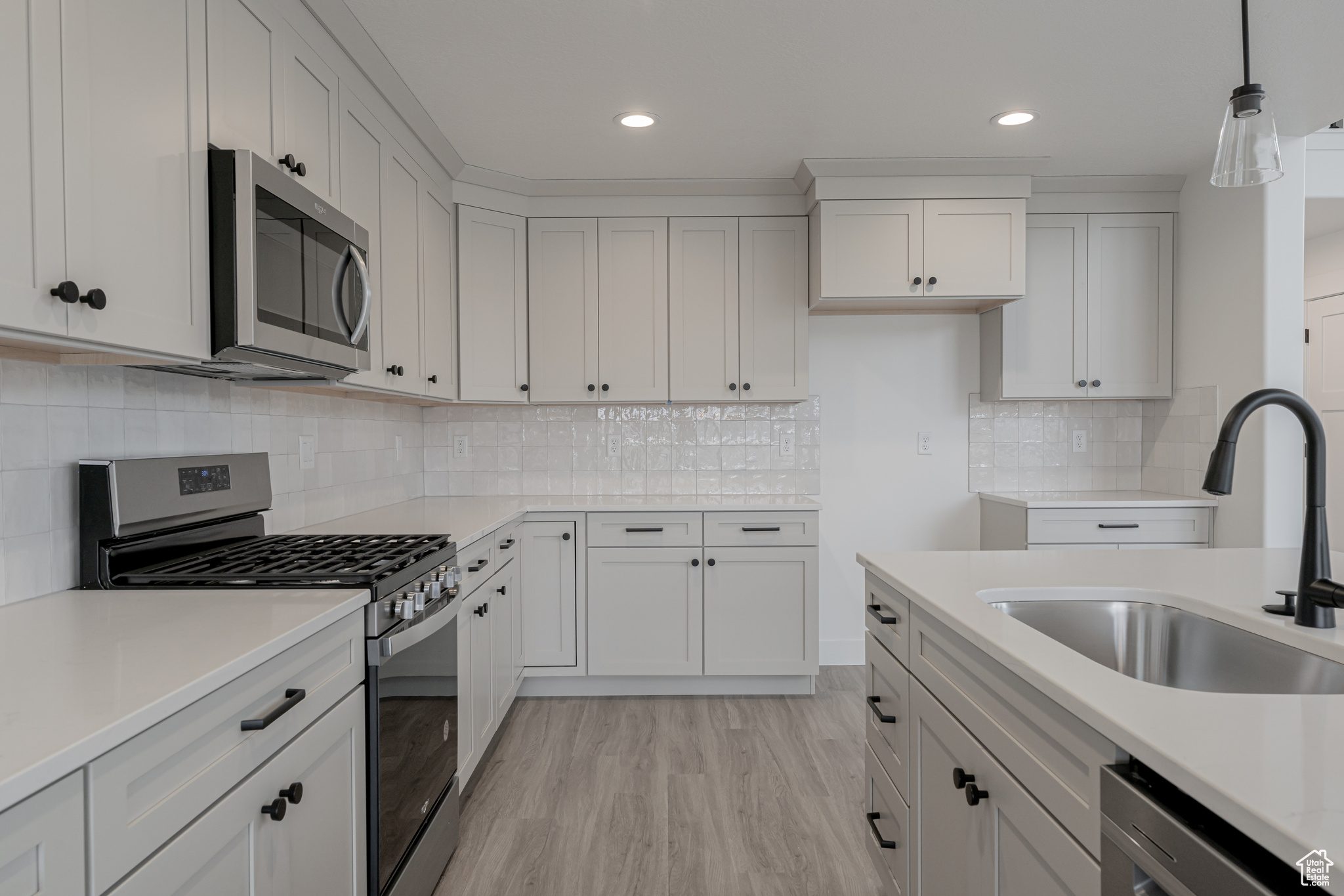 Kitchen featuring white cabinets, stainless steel appliances, sink, and light hardwood / wood-style flooring