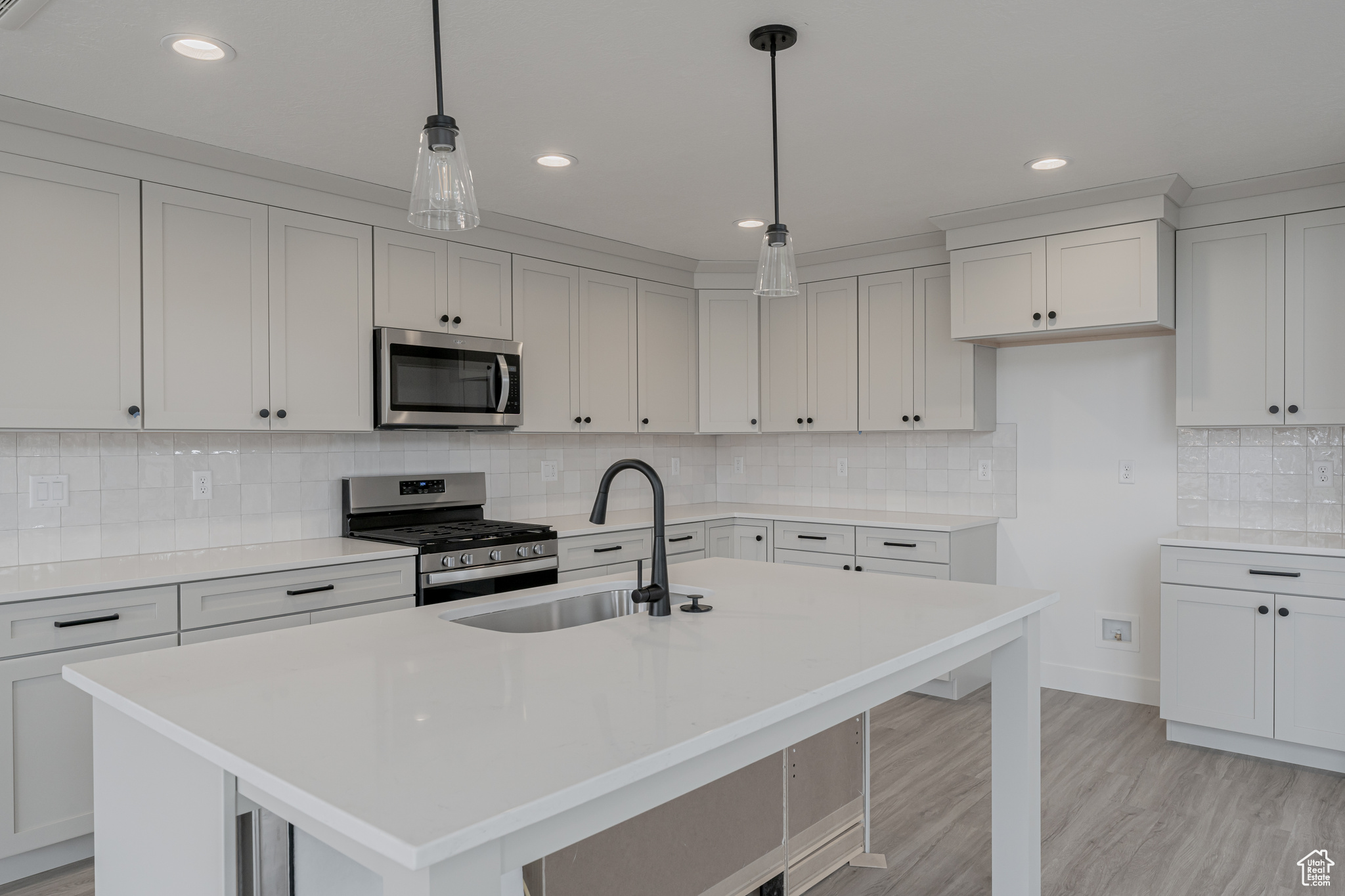 Kitchen with an island with sink, stainless steel appliances, sink, and decorative backsplash