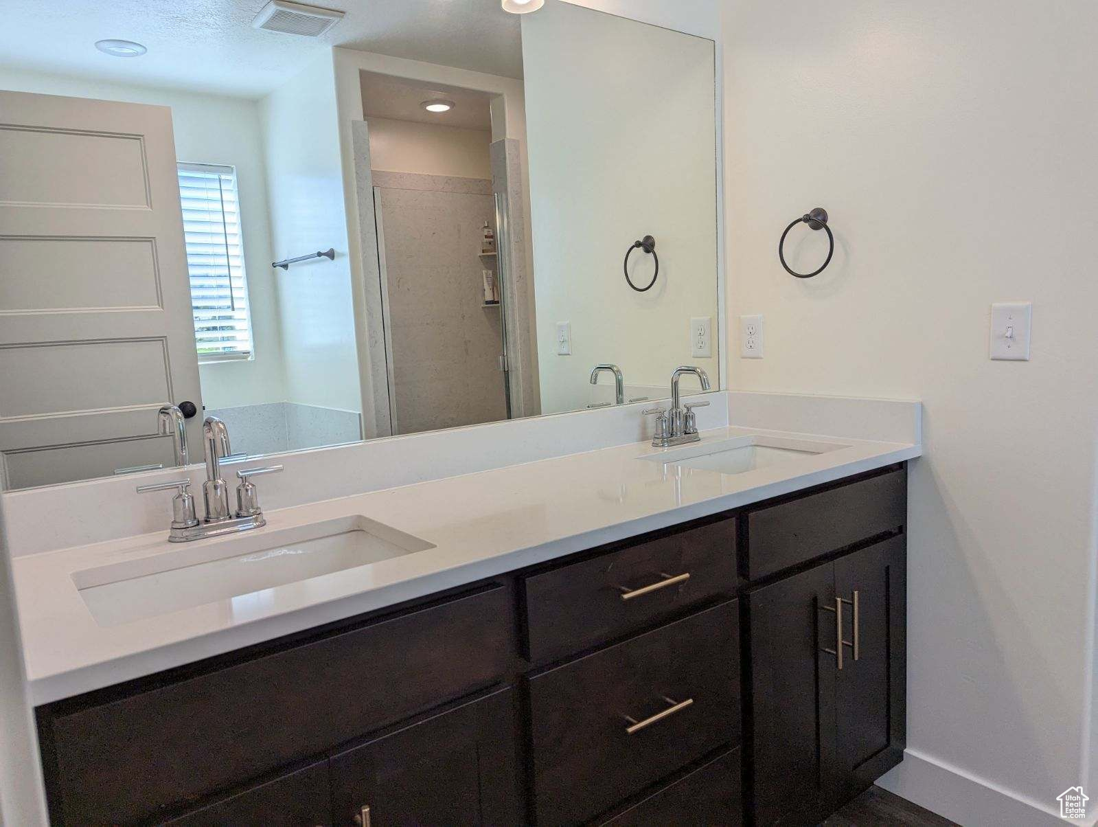 Bathroom featuring an enclosed shower, oversized vanity, and double sink