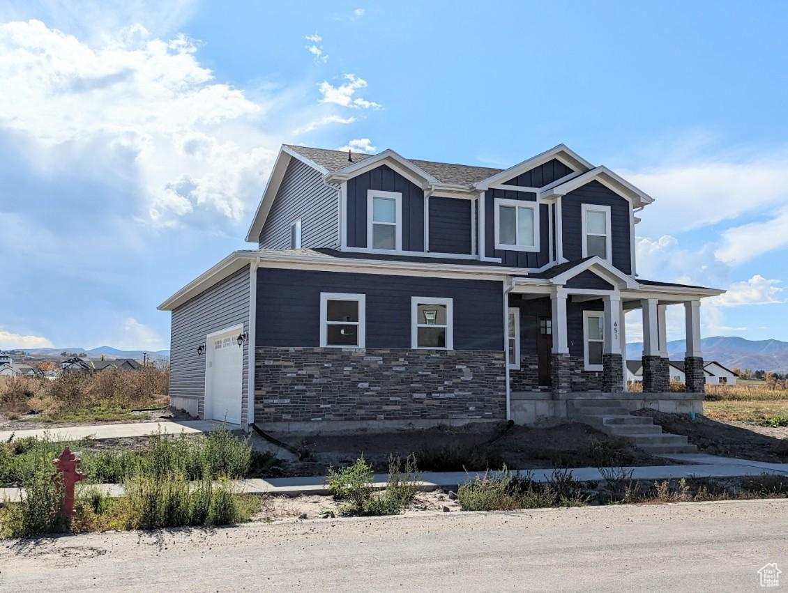 View of front of property featuring covered porch, a garage, and a mountain view