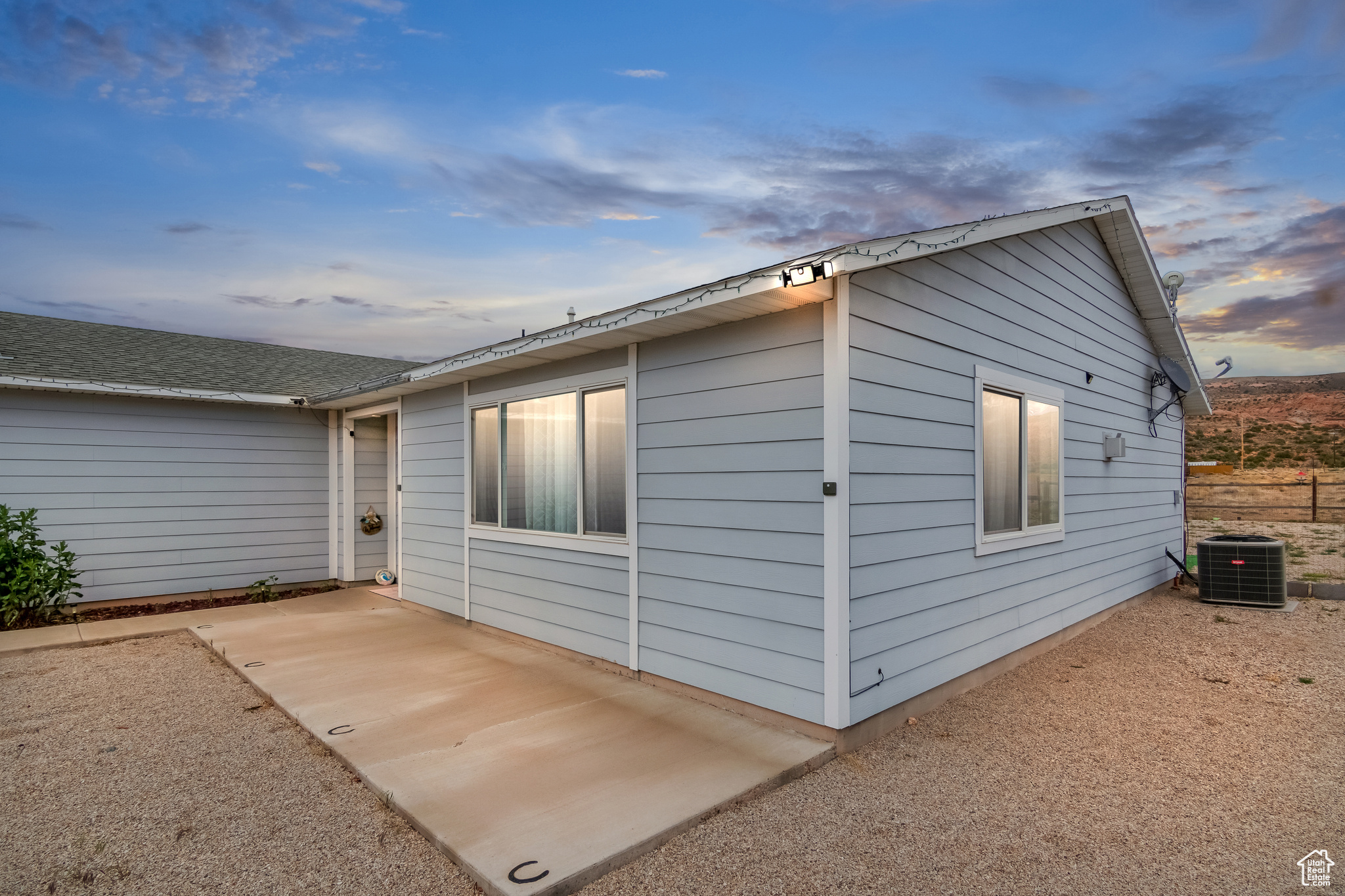 View of front of home with central AC and a patio