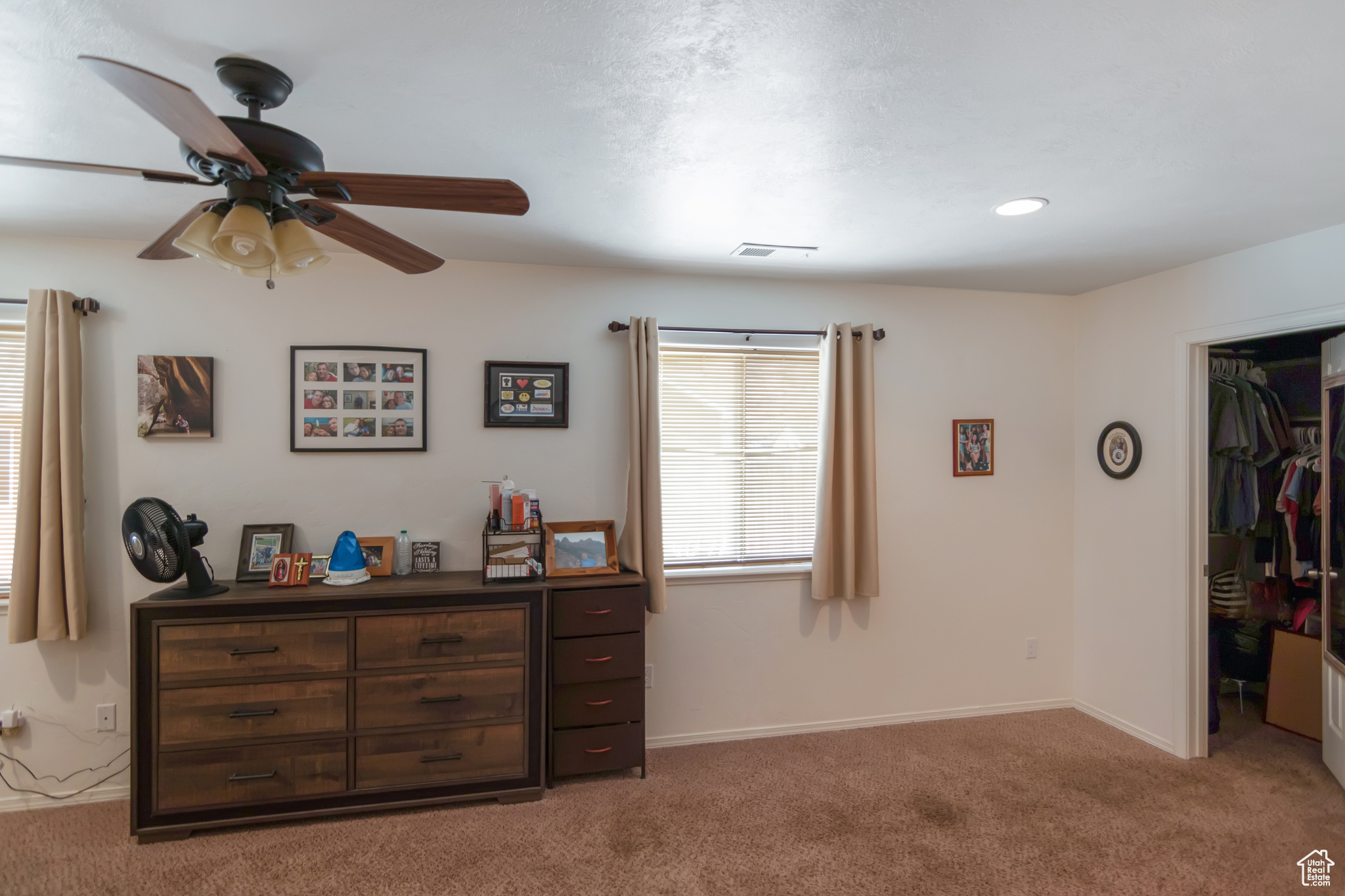 Carpeted bedroom with ceiling fan, a closet, and a walk in closet