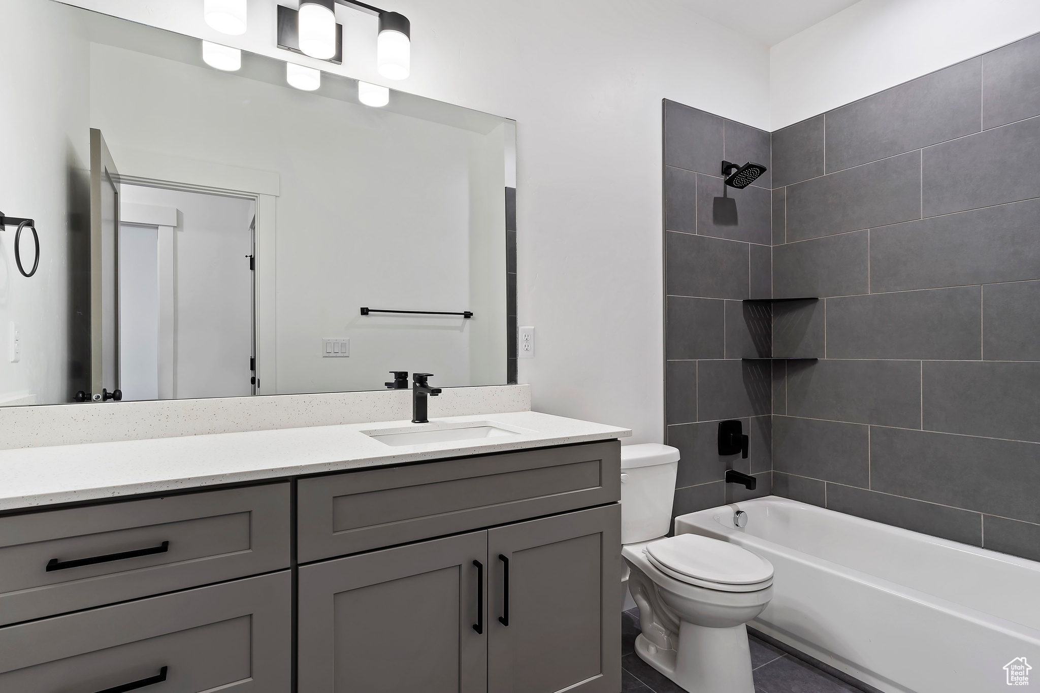 Full bathroom with tile floors, vanity, toilet, and tiled shower / bath combo