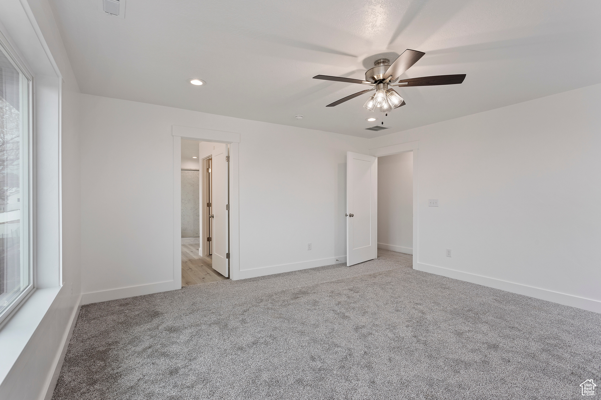 Unfurnished bedroom featuring ensuite bathroom, carpet, and ceiling fan