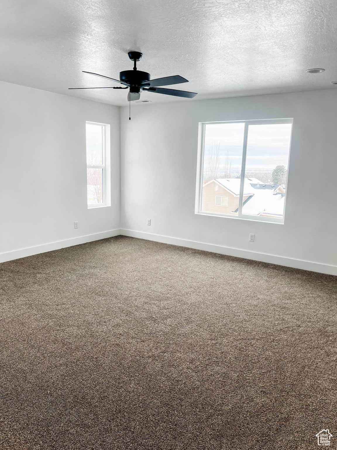 Empty room featuring ceiling fan, a textured ceiling, and carpet flooring