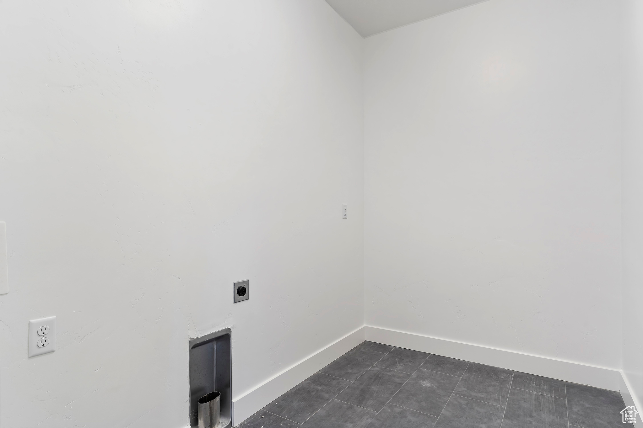 Laundry area with hookup for an electric dryer and dark tile floors