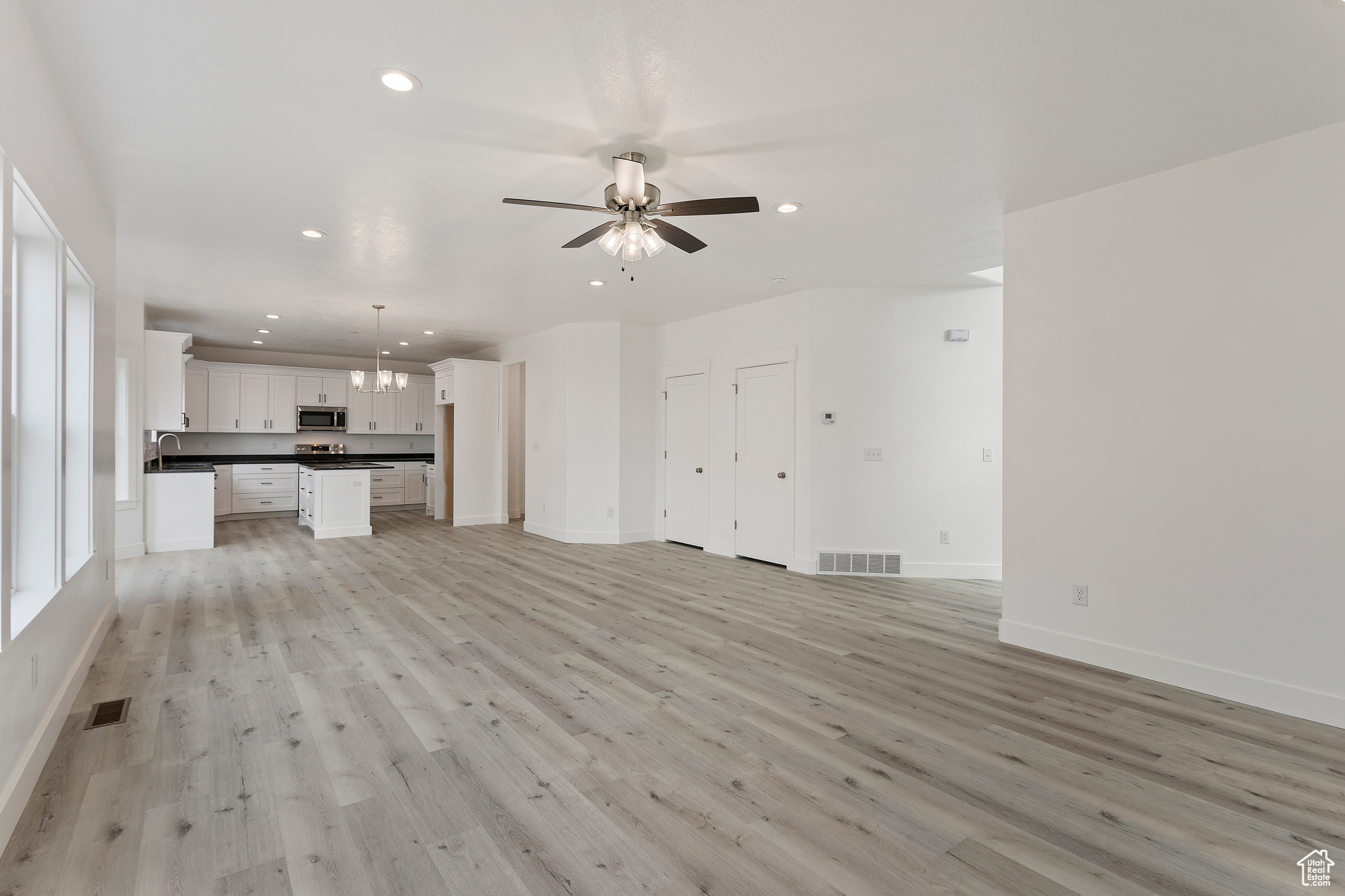 Unfurnished living room with ceiling fan and light hardwood / wood-style flooring