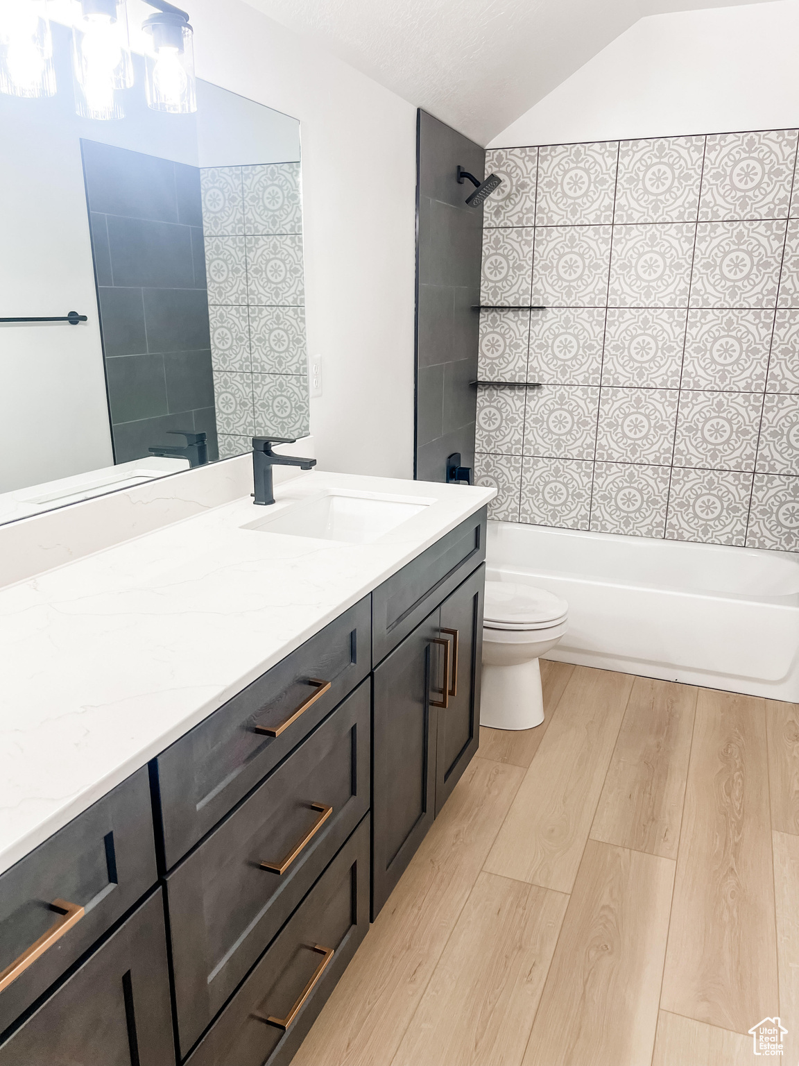 Full bathroom featuring wood-type flooring, tiled shower / bath, vanity, and toilet