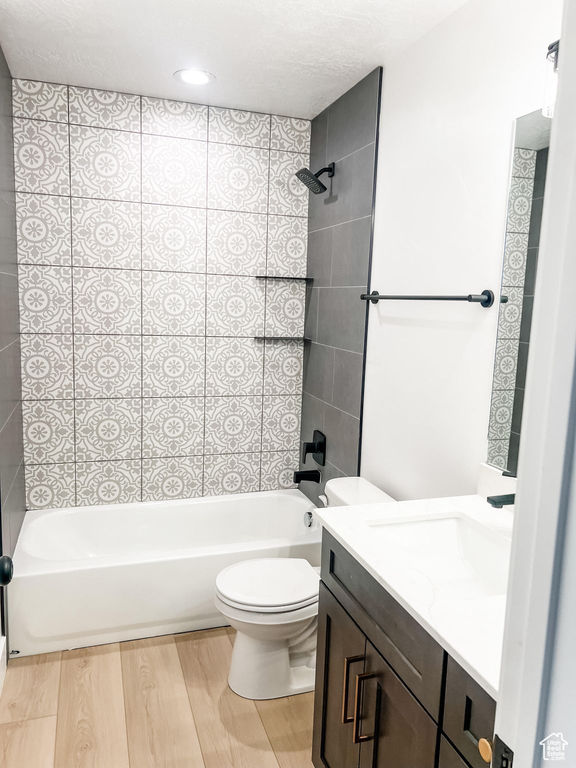 Full bathroom with tiled shower / bath, hardwood / wood-style floors, toilet, and vanity