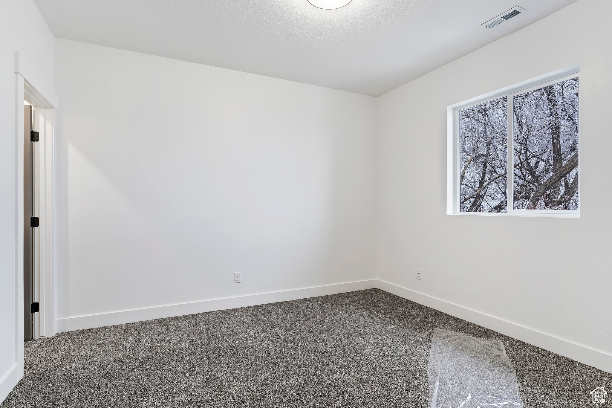 Spare room featuring dark colored carpet