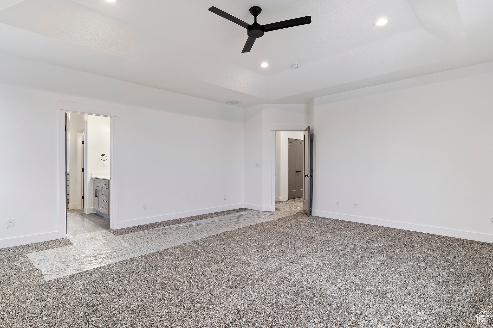 Carpeted empty room featuring a raised ceiling and ceiling fan