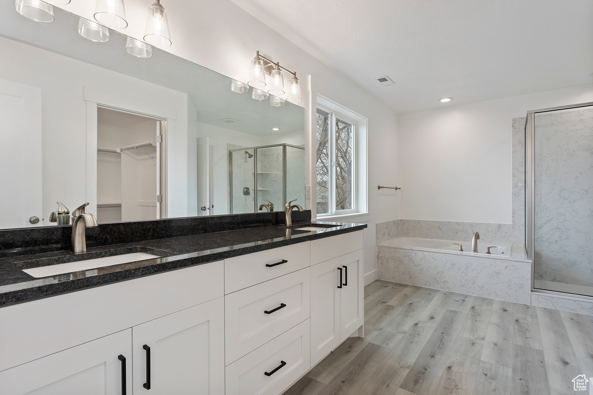 Bathroom with dual vanity, hardwood / wood-style flooring, and independent shower and bath