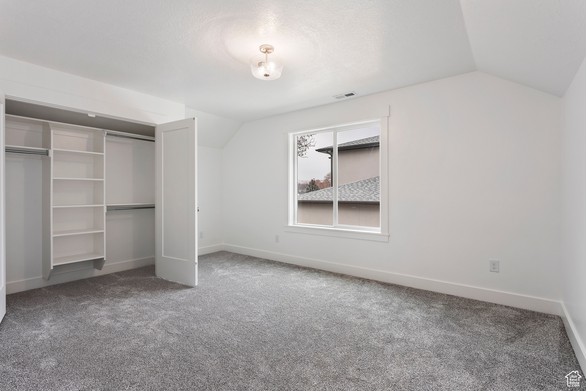 Unfurnished bedroom featuring carpet floors, lofted ceiling, and a closet