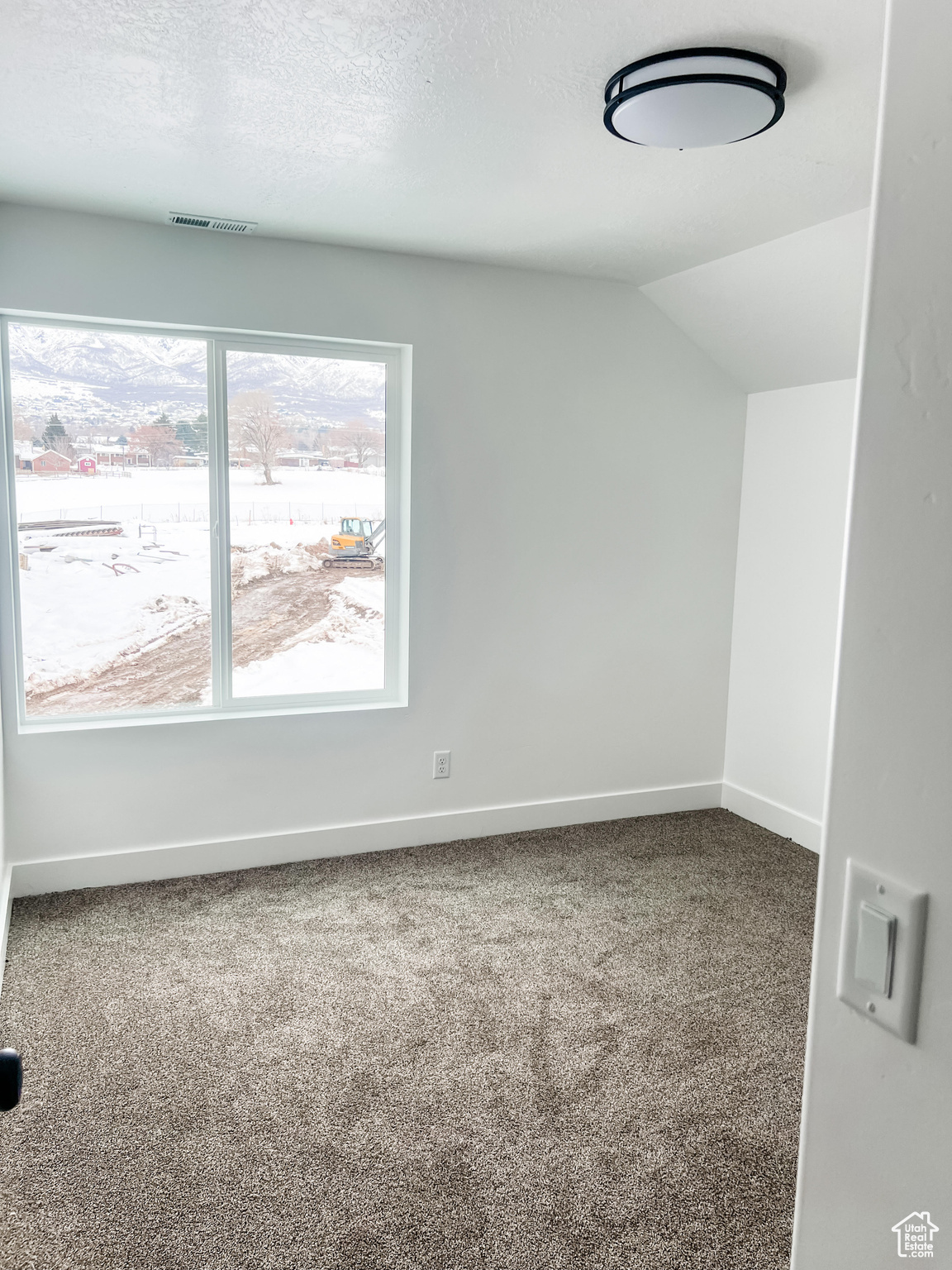 Unfurnished room with vaulted ceiling, carpet, and a textured ceiling