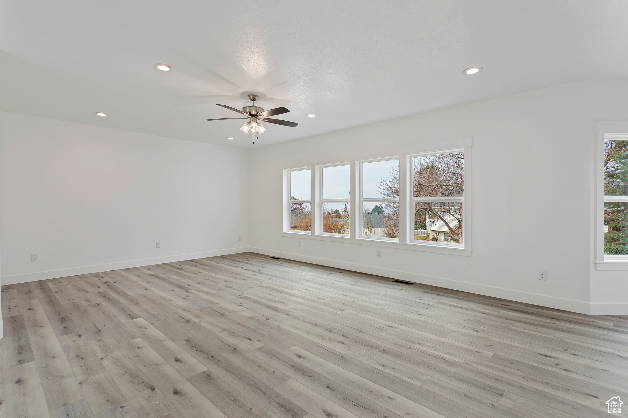 Unfurnished room with a healthy amount of sunlight, ceiling fan, and light hardwood / wood-style flooring