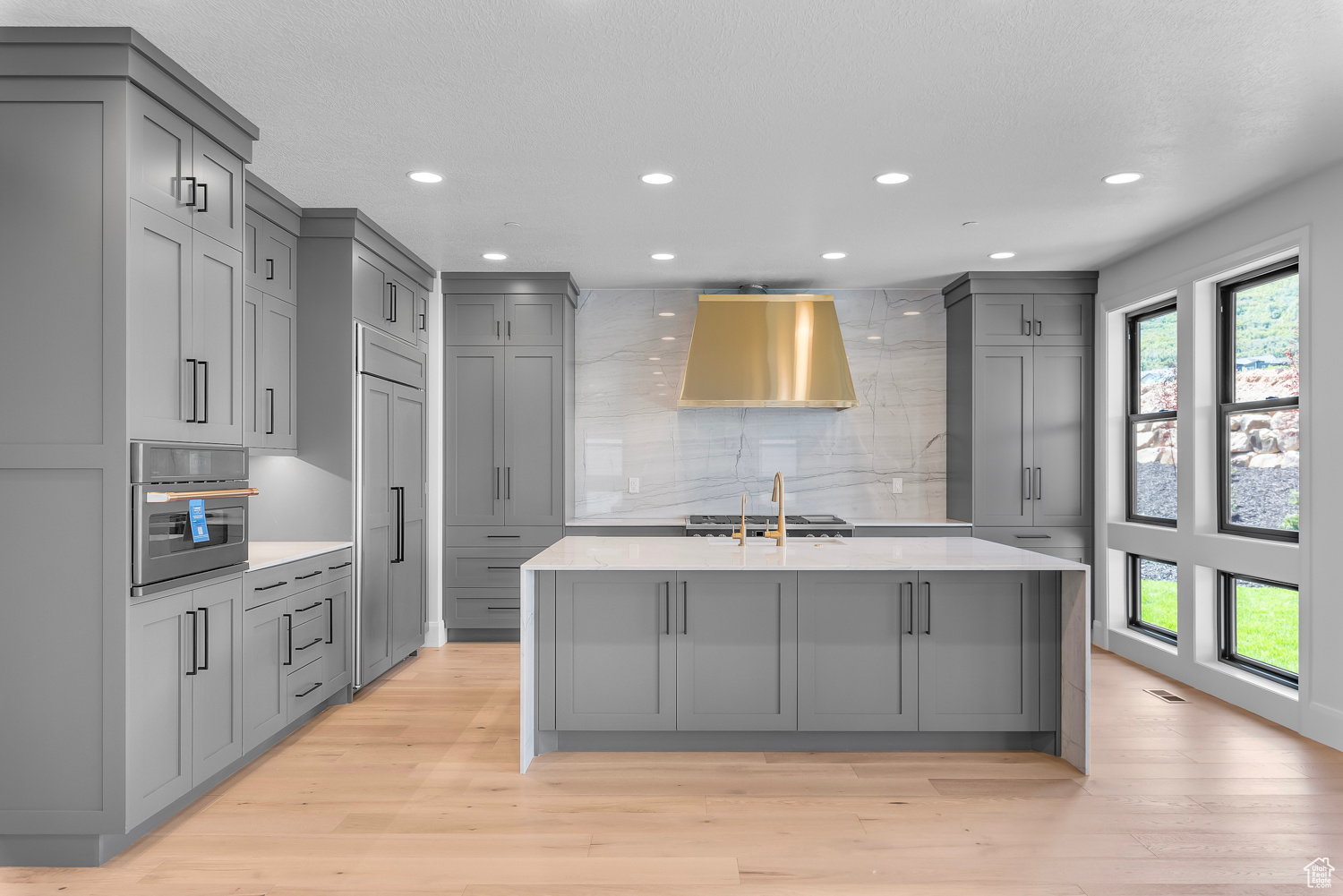 Kitchen with gray cabinetry, plenty of natural light, and light hardwood / wood-style floors