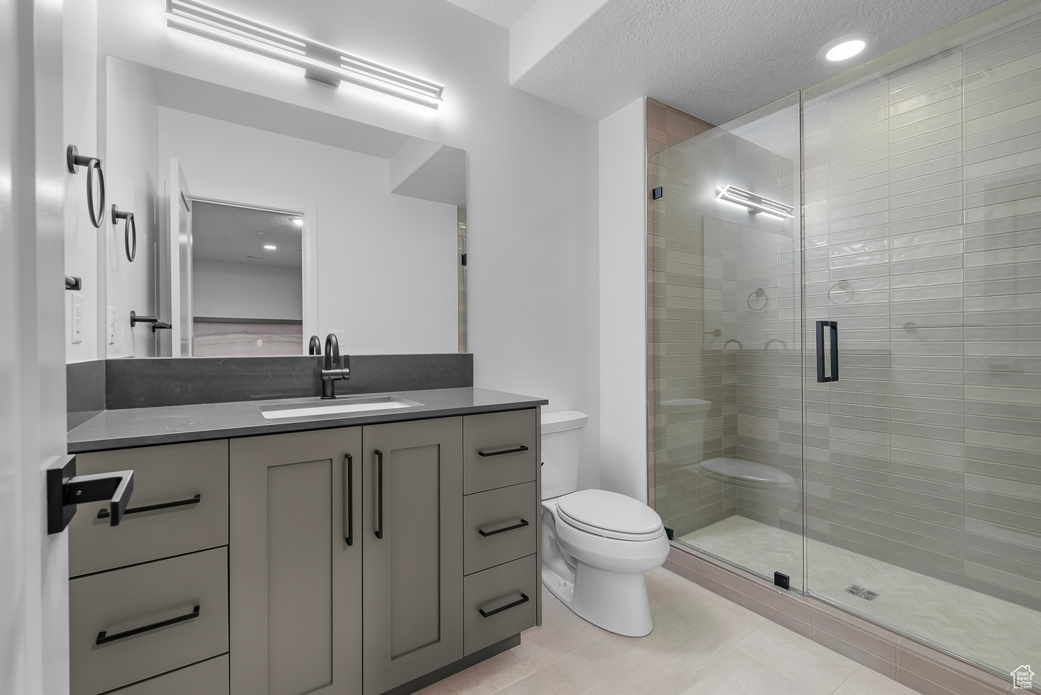 Bathroom with tile patterned flooring, vanity, walk in shower, and toilet