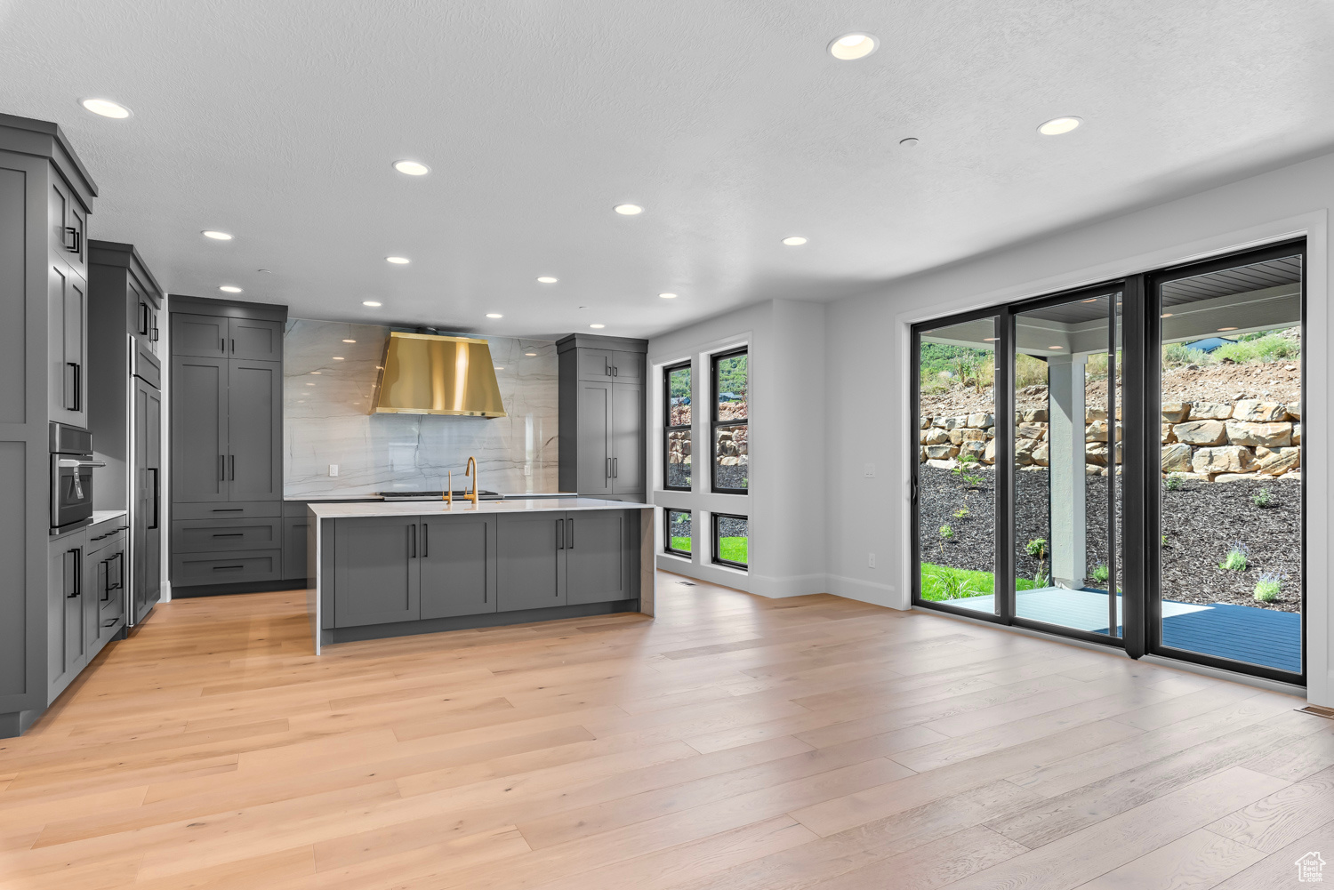 Kitchen featuring a wealth of natural light, light hardwood / wood-style flooring, a kitchen island with sink, and gray cabinets