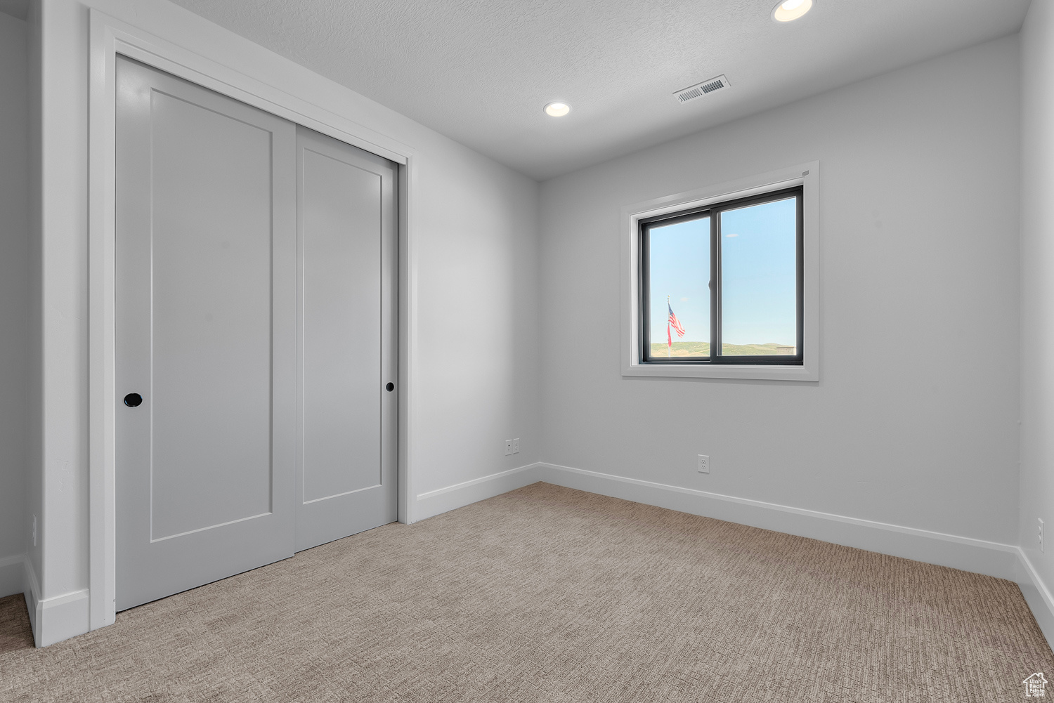 Unfurnished bedroom with a closet and light carpet