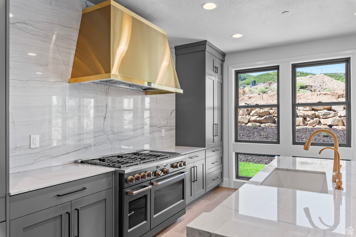 Kitchen featuring wall chimney range hood, tasteful backsplash, gray cabinetry, double oven range, and a wealth of natural light