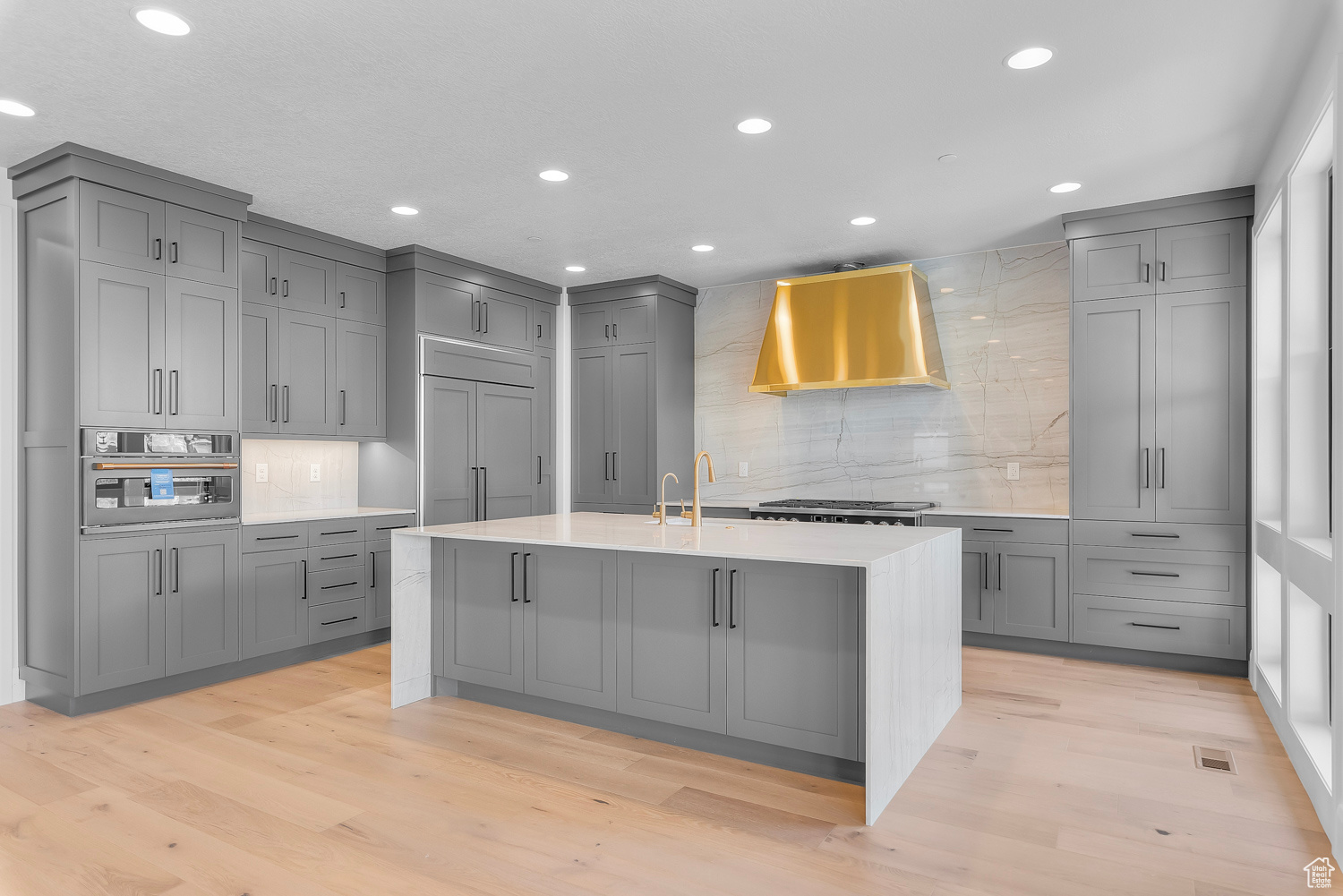 Kitchen with light hardwood / wood-style floors, paneled built in fridge, wall chimney exhaust hood, and tasteful backsplash